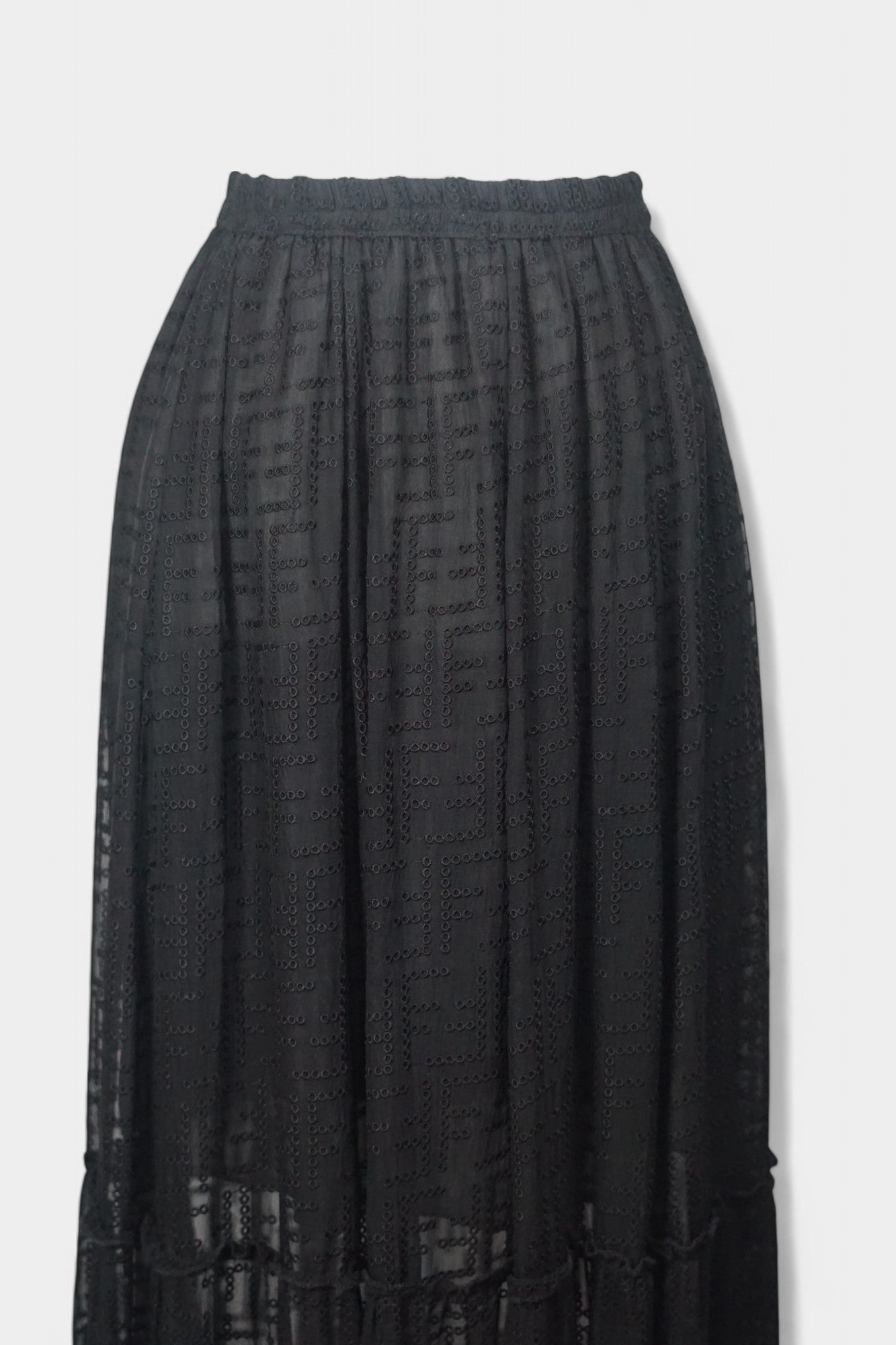 Semi-sheer noir skirt with intricate geometric cutouts, featuring a comfortable elastic waistband and a tiered flounce hem.