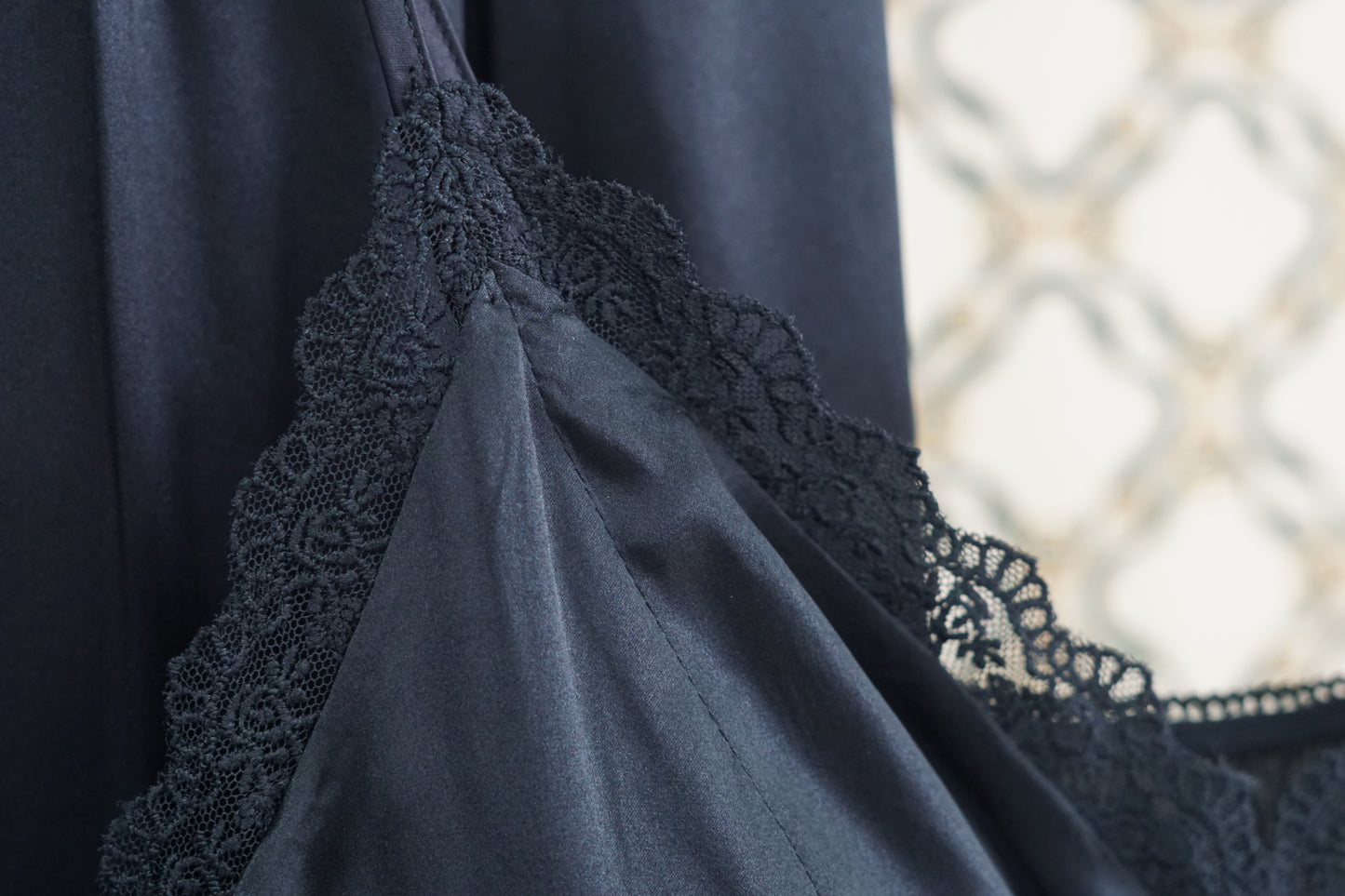 Black silk two-piece set featuring a lace-trimmed camisole top with button details and matching wide-leg trousers.