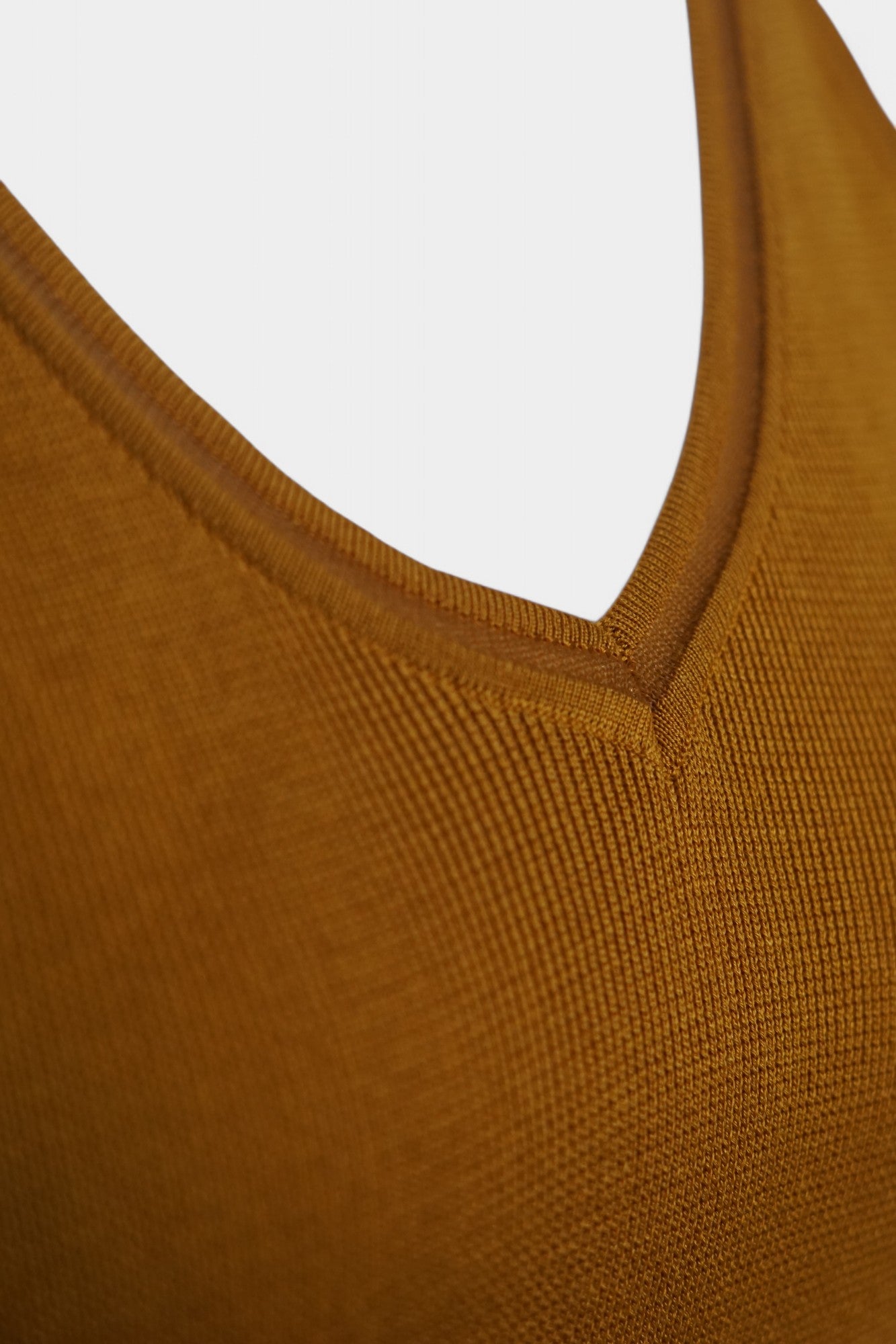 Rear view of a mustard-colored knit tank top on a white mannequin, featuring wide straps and a clean V-shaped neckline at the back.