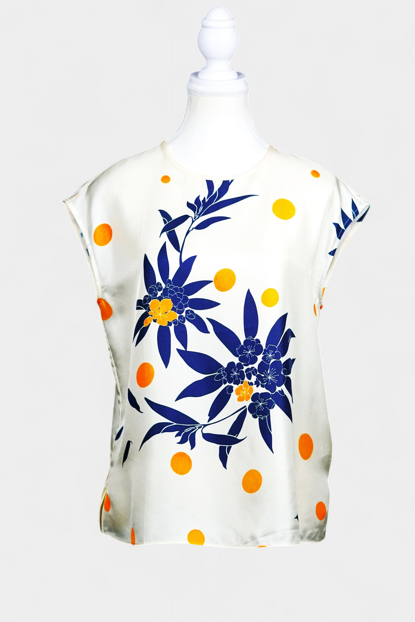 Cream silk sleeveless top featuring blue floral patterns and orange polka dots