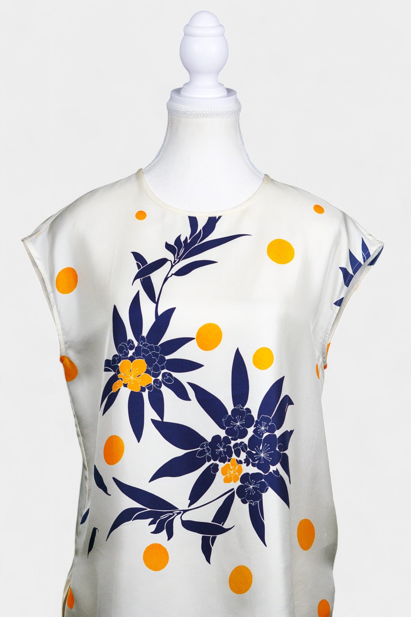 Cream silk sleeveless top featuring blue floral patterns and orange polka dots