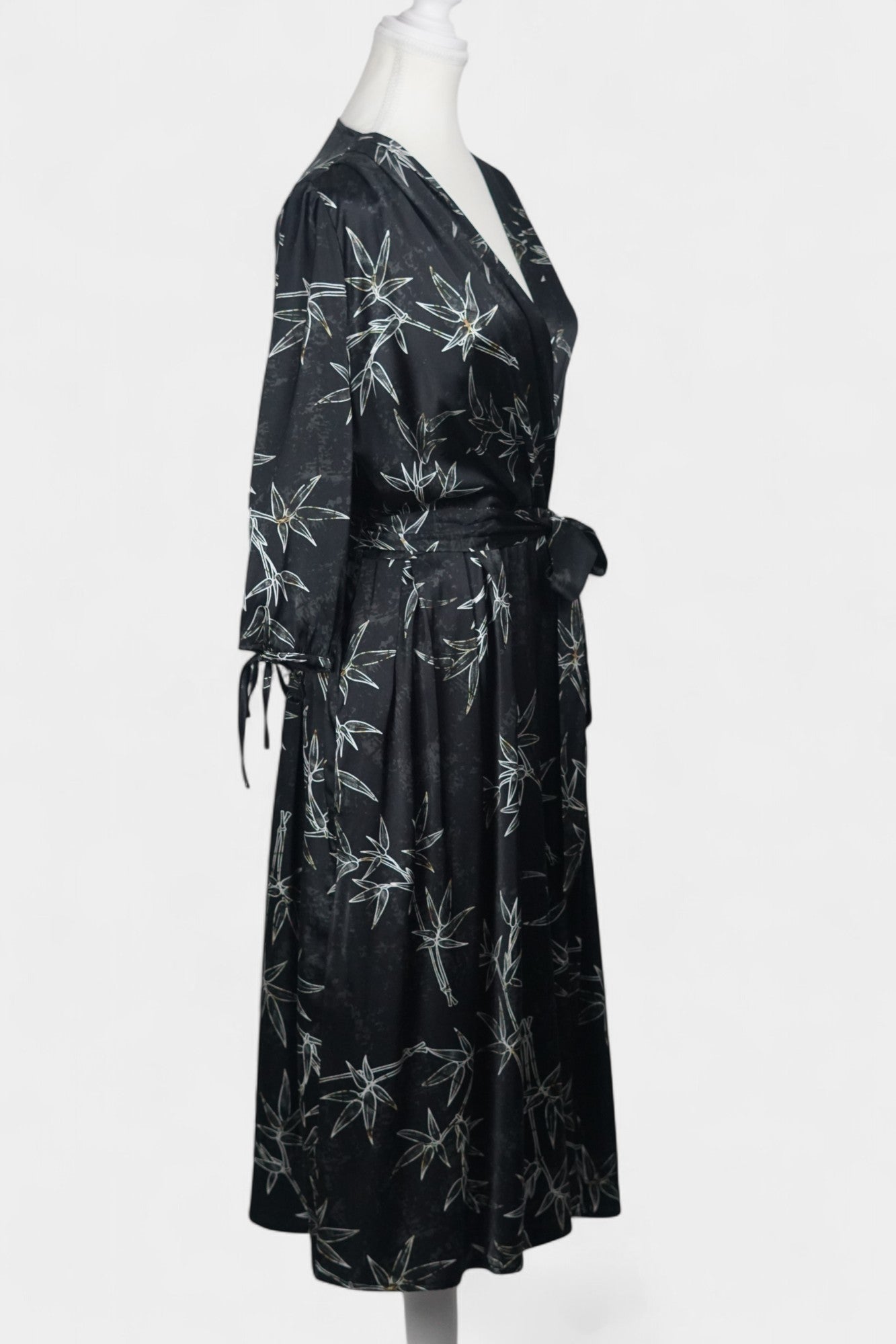 Women's black Gambiered Guangdong Gauze wrap dress with white bamboo leaf print and tie-cuff sleeves.