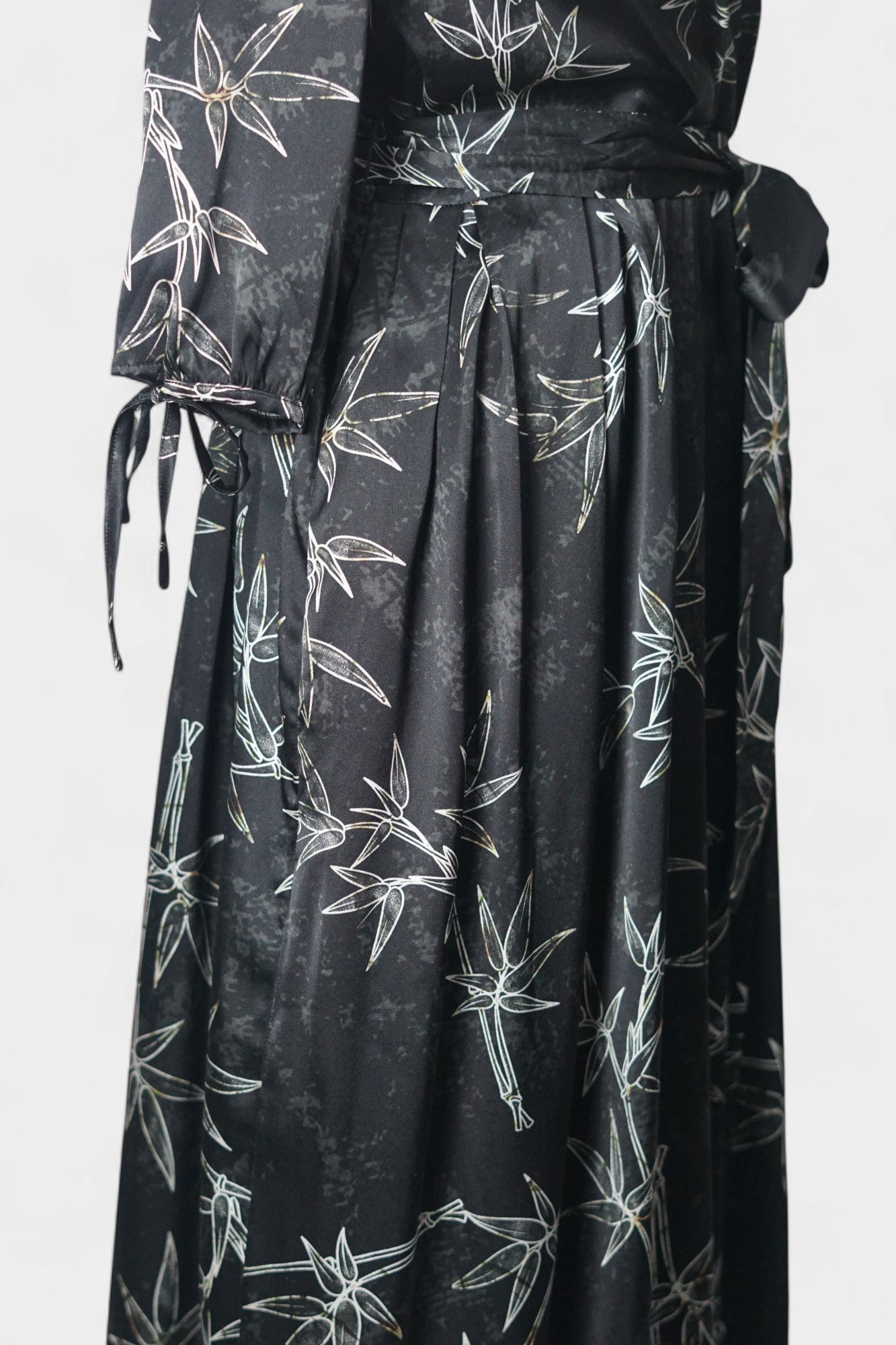 Women's black Gambiered Guangdong Gauze wrap dress with white bamboo leaf print and tie-cuff sleeves.
