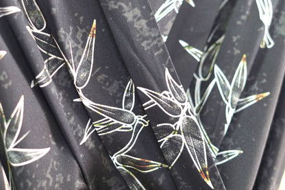 Women's black Gambiered Guangdong Gauze wrap dress with white bamboo leaf print and tie-cuff sleeves.