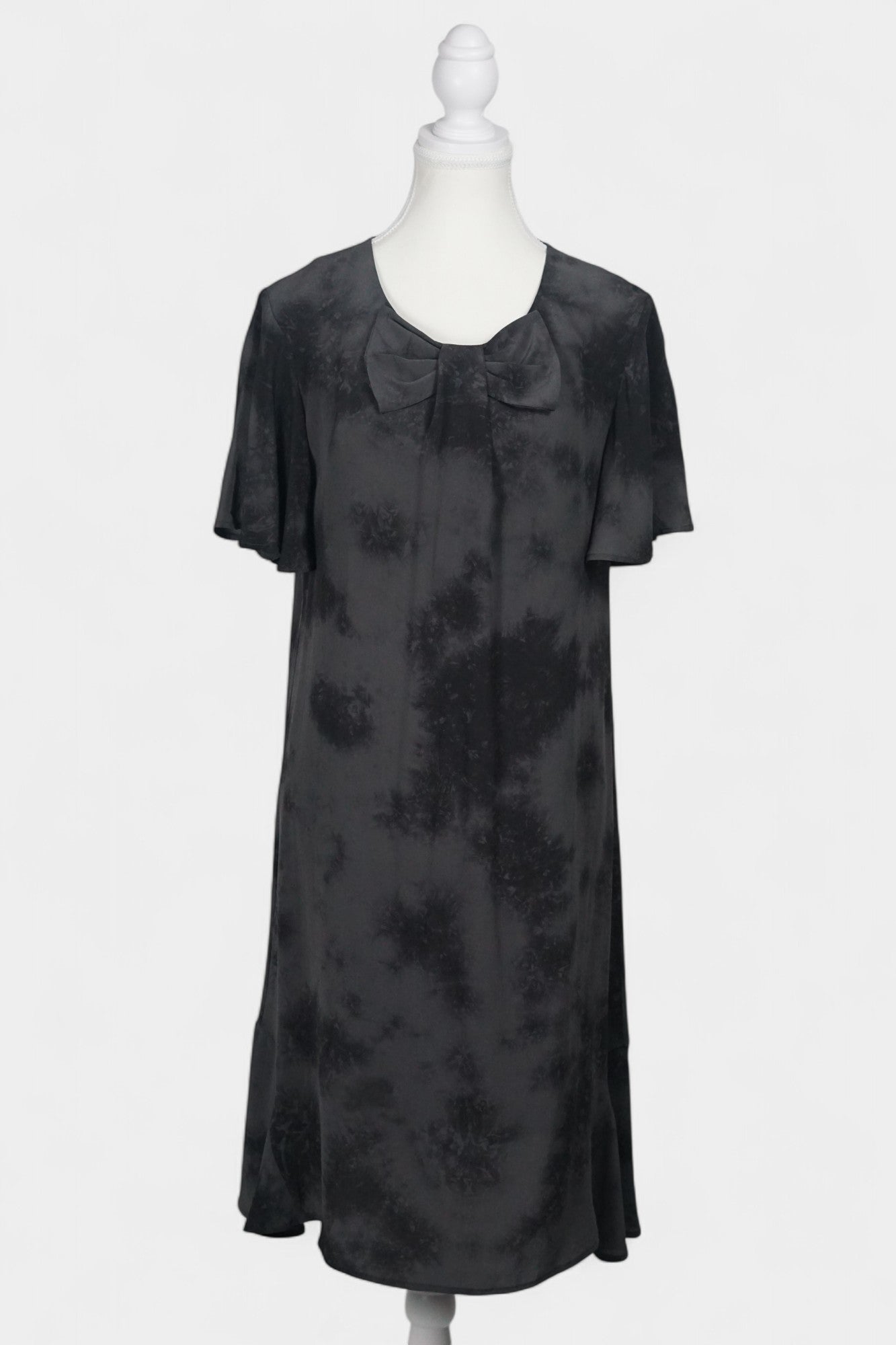 Women's black and grey patterned silk dress with a bow neckline and short flutter sleeves on a mannequin.