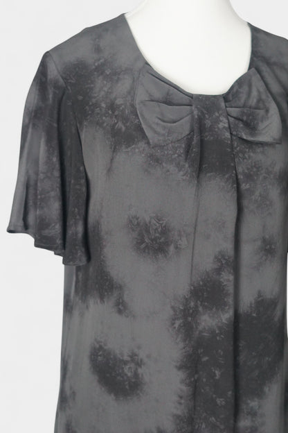 Women's black and grey patterned silk dress with a bow neckline and short flutter sleeves on a mannequin.
