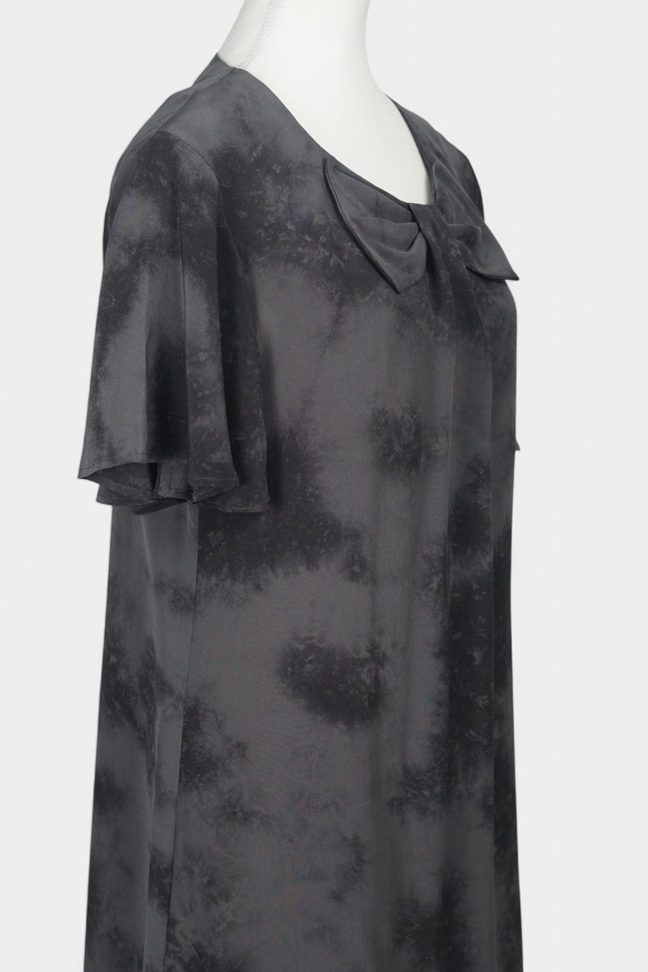 Women's black and grey patterned silk dress with a bow neckline and short flutter sleeves on a mannequin