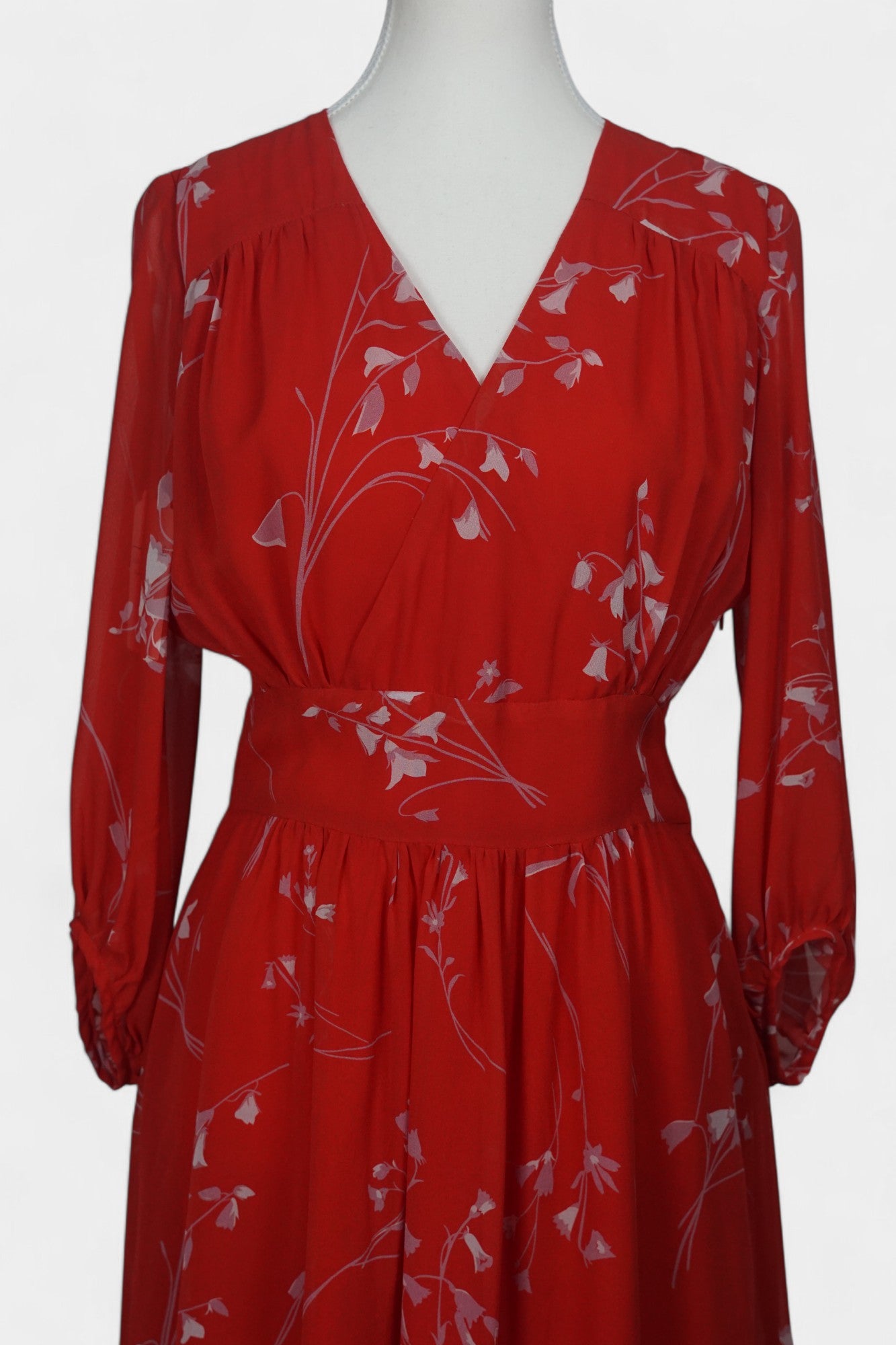 Women's red silk dress with white floral print, featuring a V-neck, wide waistband, and long sheer sleeves