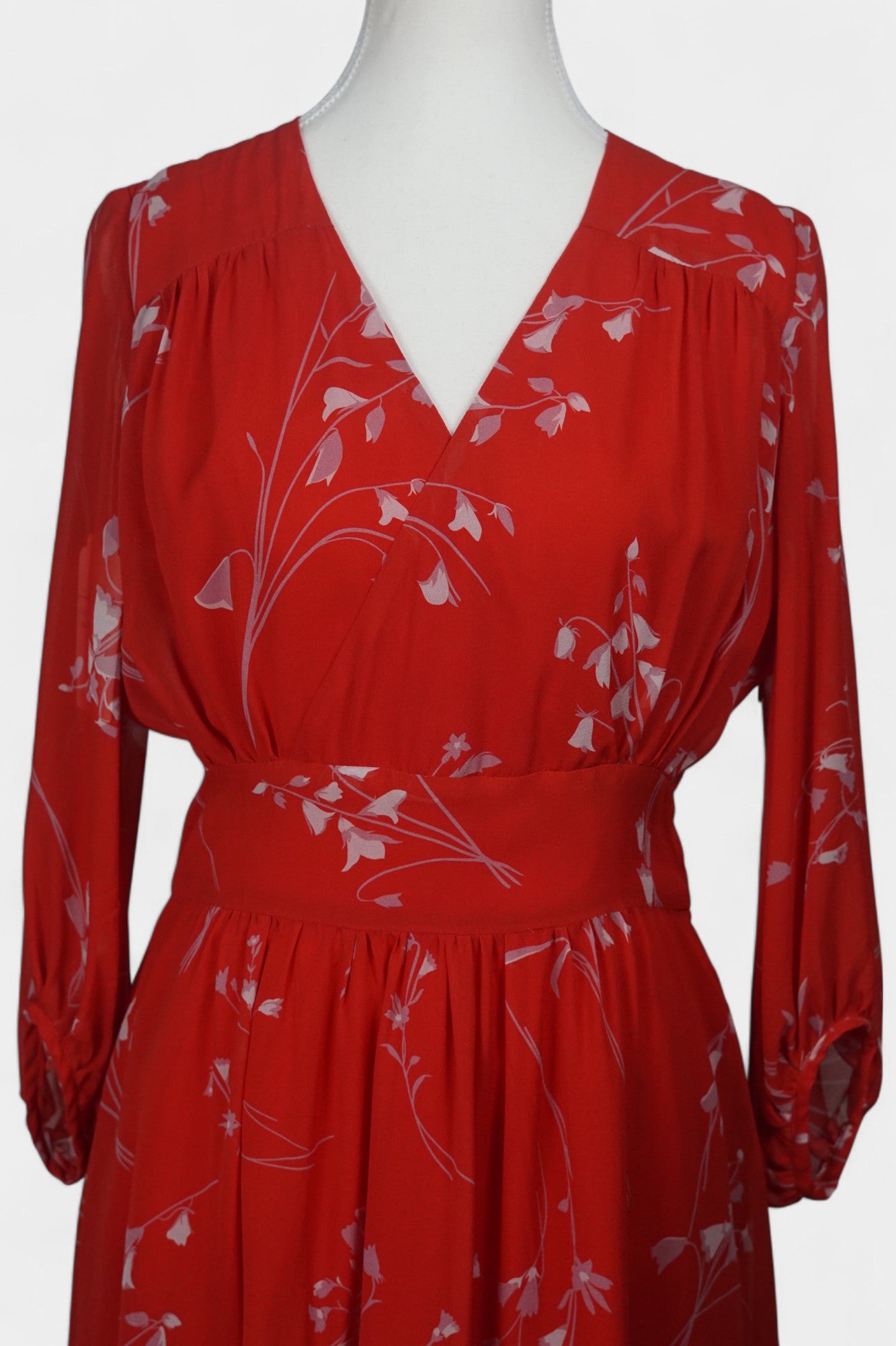 Women's red silk dress with white floral print, featuring a V-neck, wide waistband, and long sheer sleeves