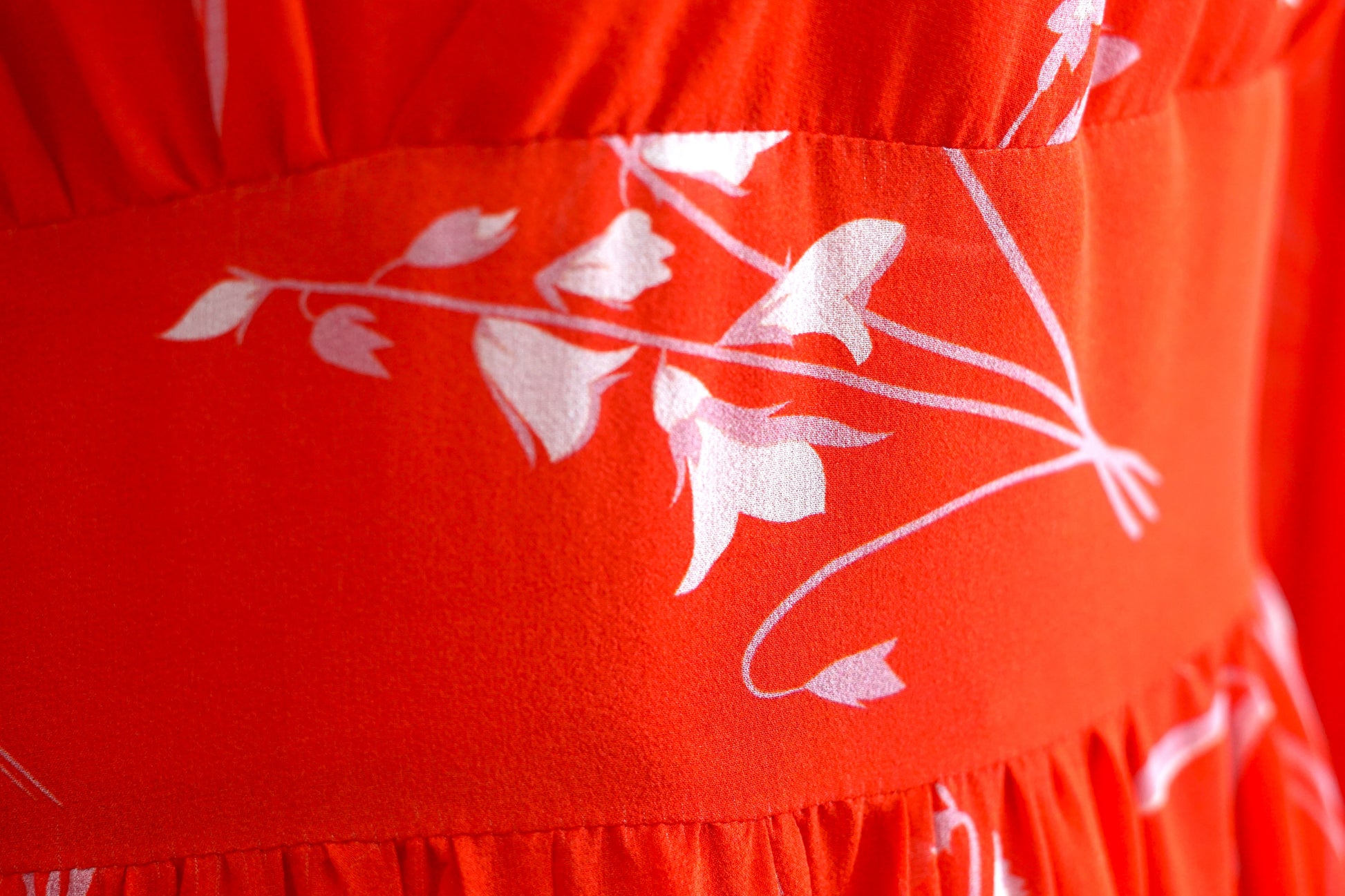 Women's red silk dress with white floral print, featuring a V-neck, wide waistband, and long sheer sleeves