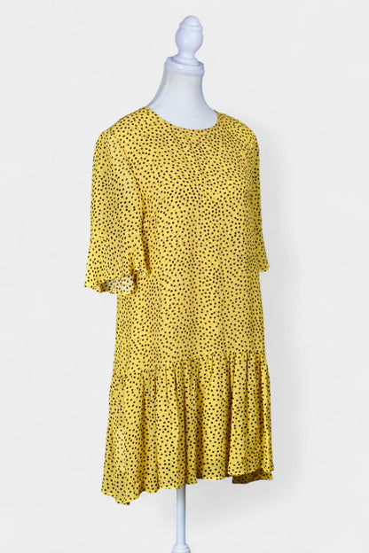 Women's yellow silk dress with black polka dots, featuring elbow-length ruffled sleeves and a gathered drop-waist hem.
