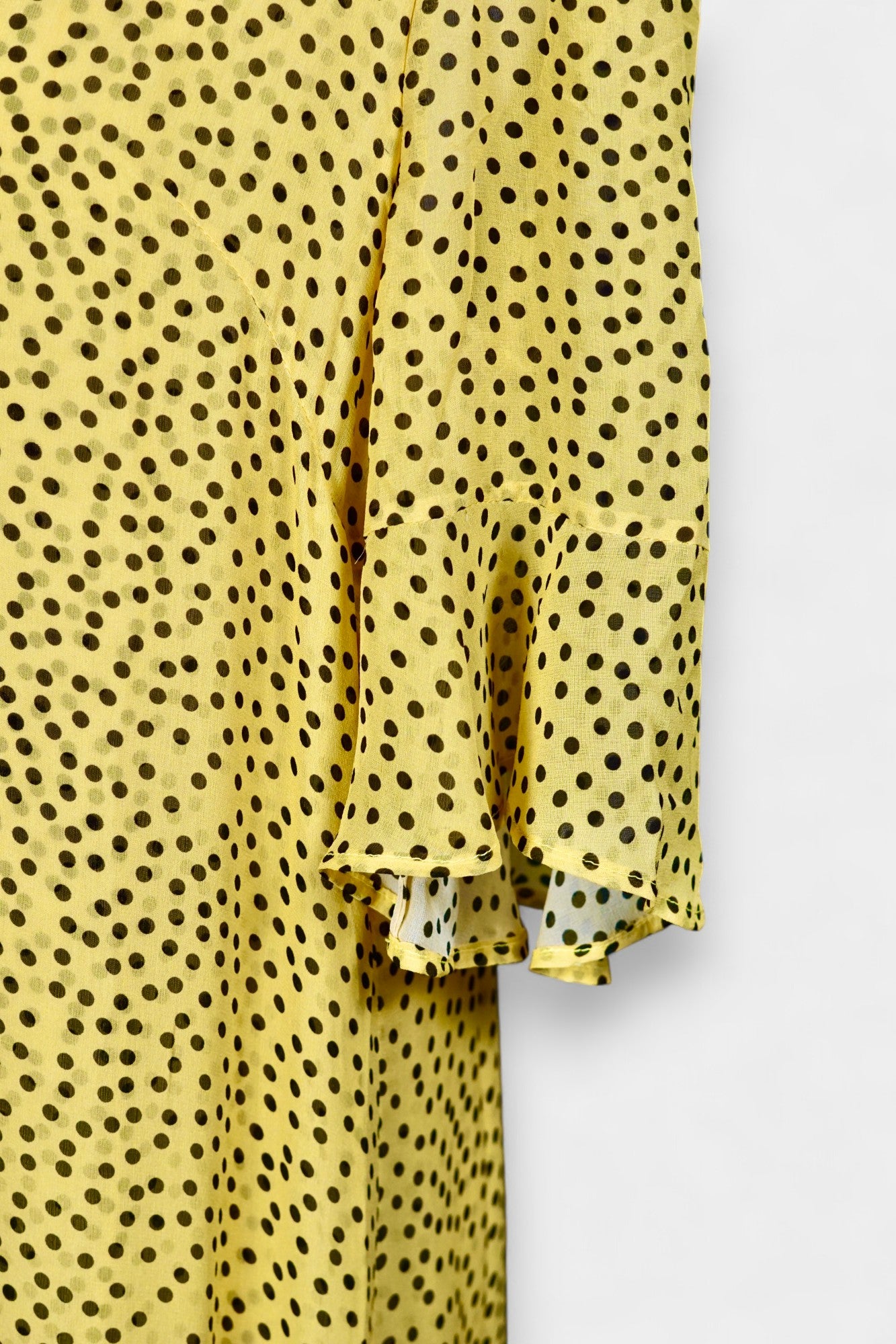 Women's yellow silk dress with black polka dots, featuring elbow-length ruffled sleeves and a gathered drop-waist hem.