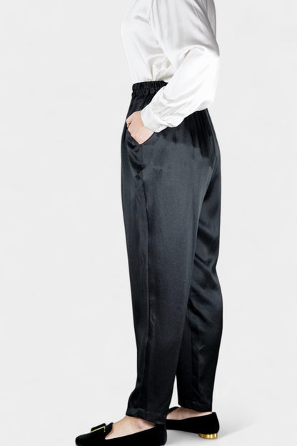 Black Mulberry silk trousers featuring elastic waistband and tapered leg design.