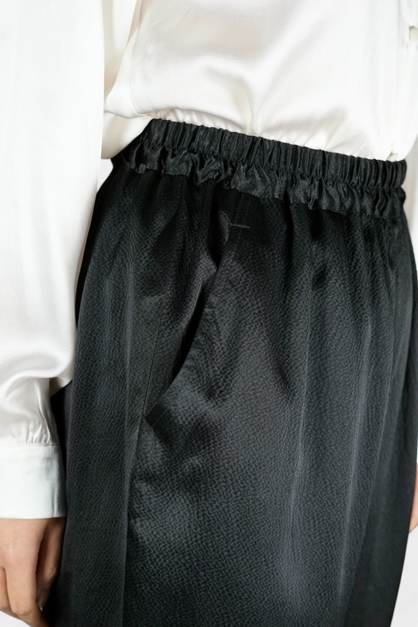 Black Mulberry silk trousers featuring elastic waistband and tapered leg design.