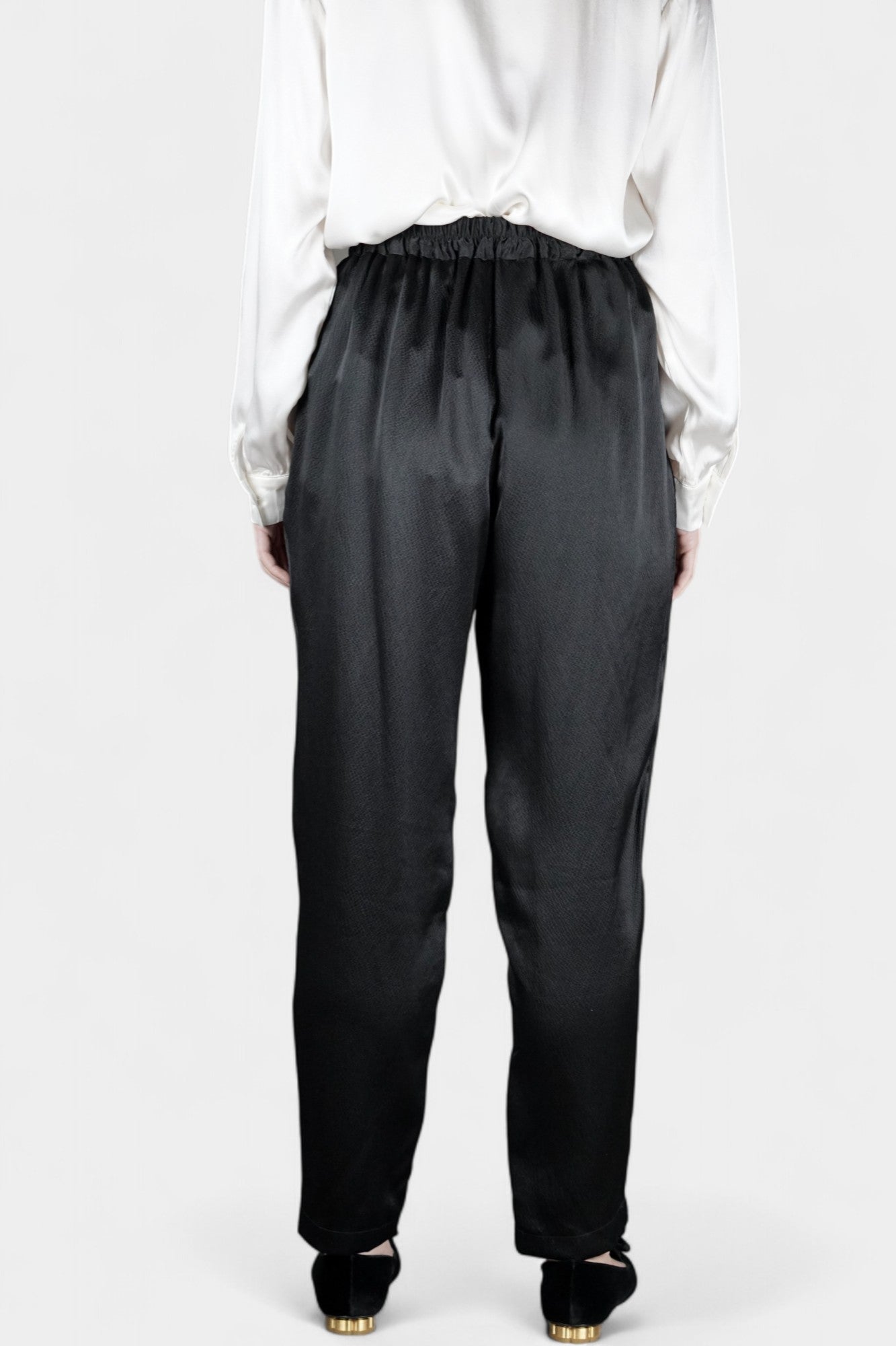 Black Mulberry silk trousers featuring elastic waistband and tapered leg design.