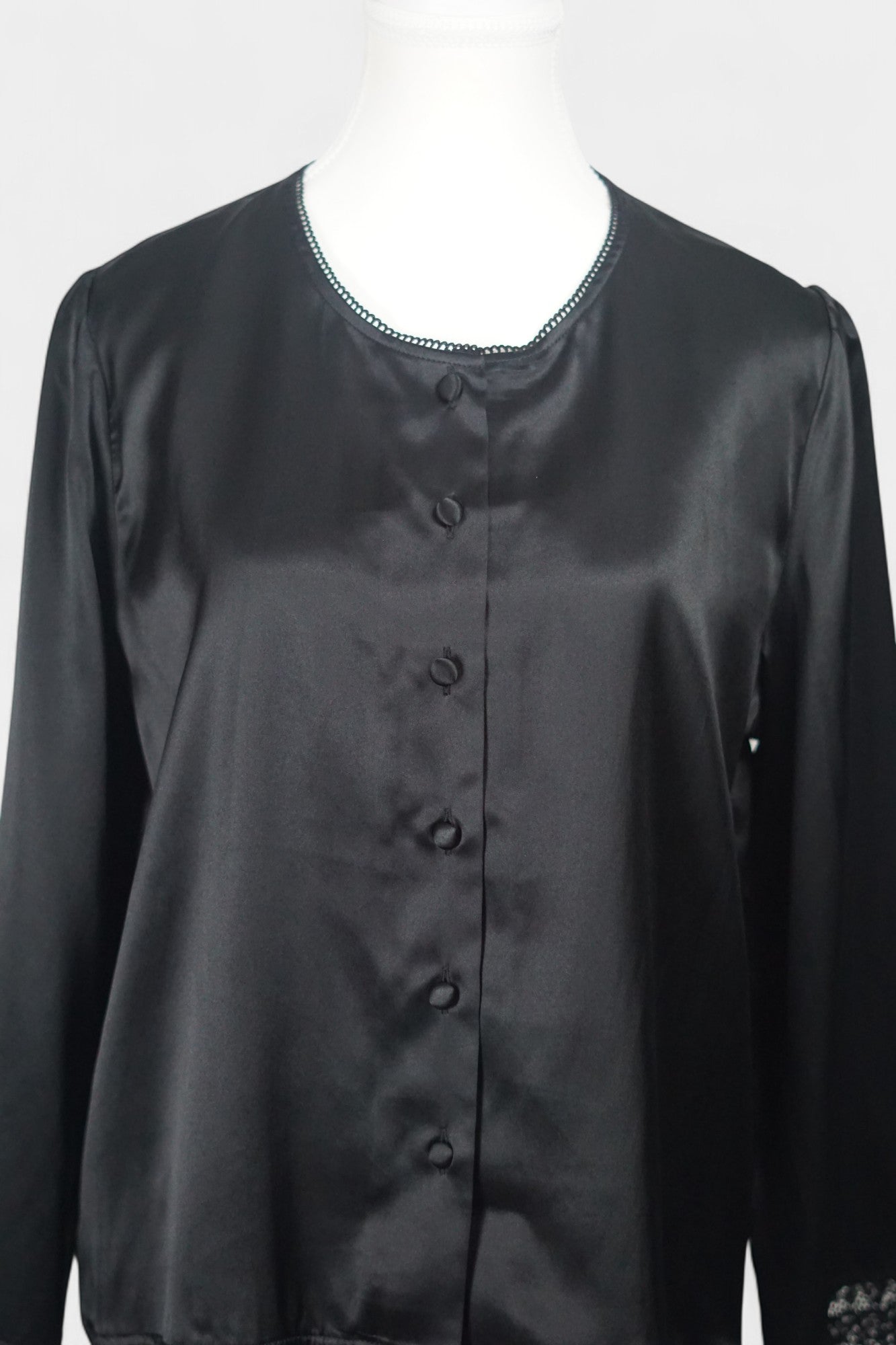 Black silk jacket featuring delicate lace trim on cuffs and hem, with button-down front