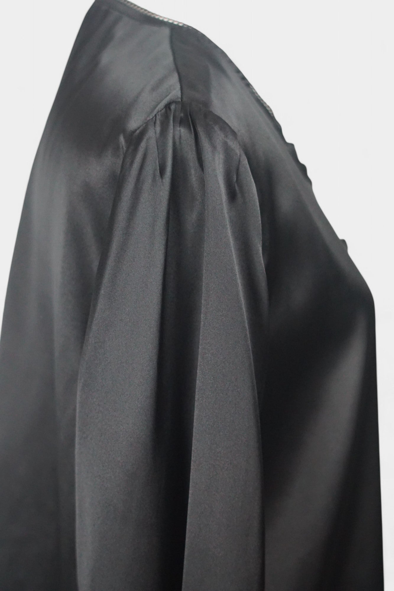 Black silk jacket featuring delicate lace trim on cuffs and hem, with button-down front