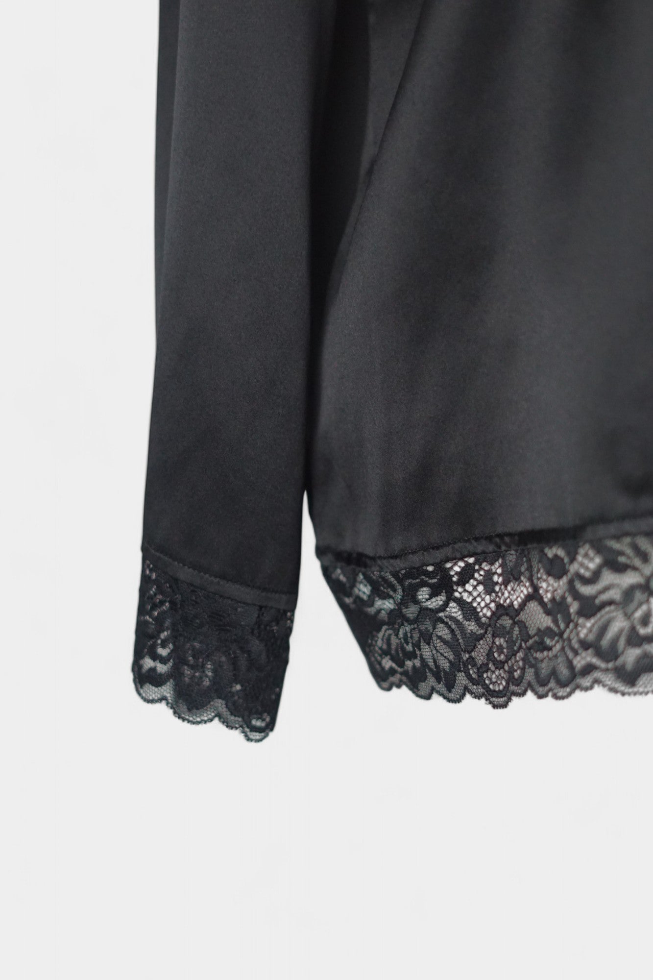 Black silk jacket featuring delicate lace trim on cuffs and hem, with button-down front
