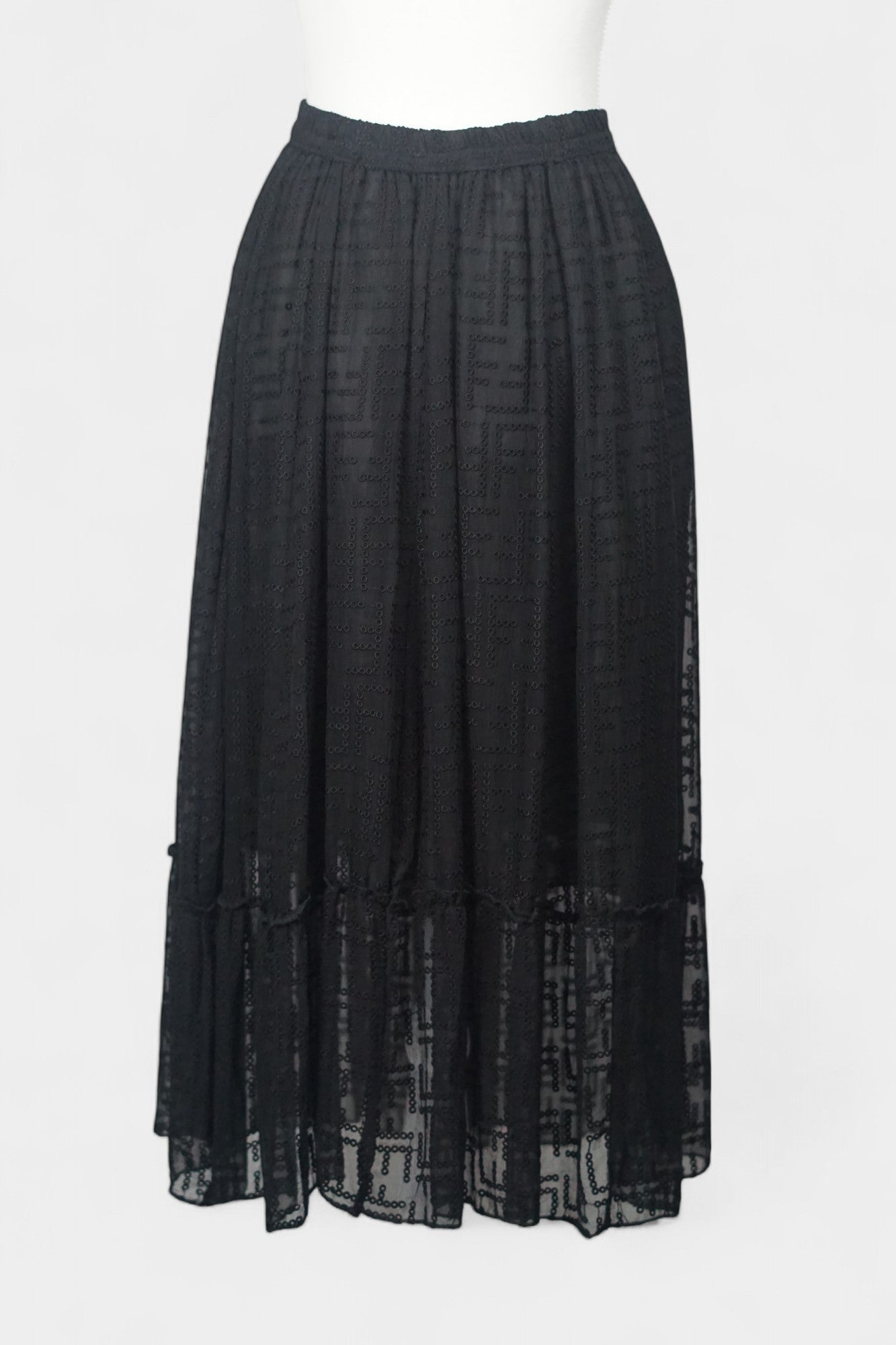Semi-sheer noir skirt with intricate geometric cutouts, featuring a comfortable elastic waistband and a tiered flounce hem.