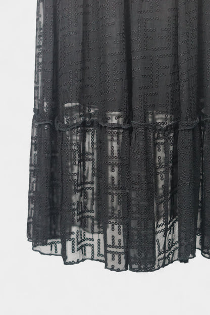 Semi-sheer noir skirt with intricate geometric cutouts, featuring a comfortable elastic waistband and a tiered flounce hem.