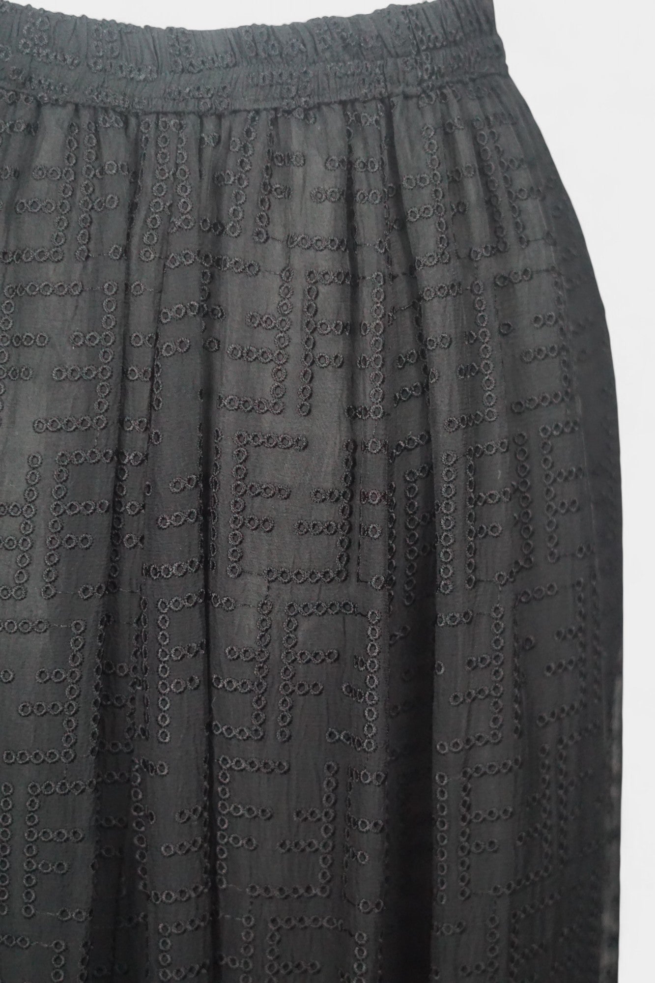 Semi-sheer noir skirt with intricate geometric cutouts, featuring a comfortable elastic waistband and a tiered flounce hem.