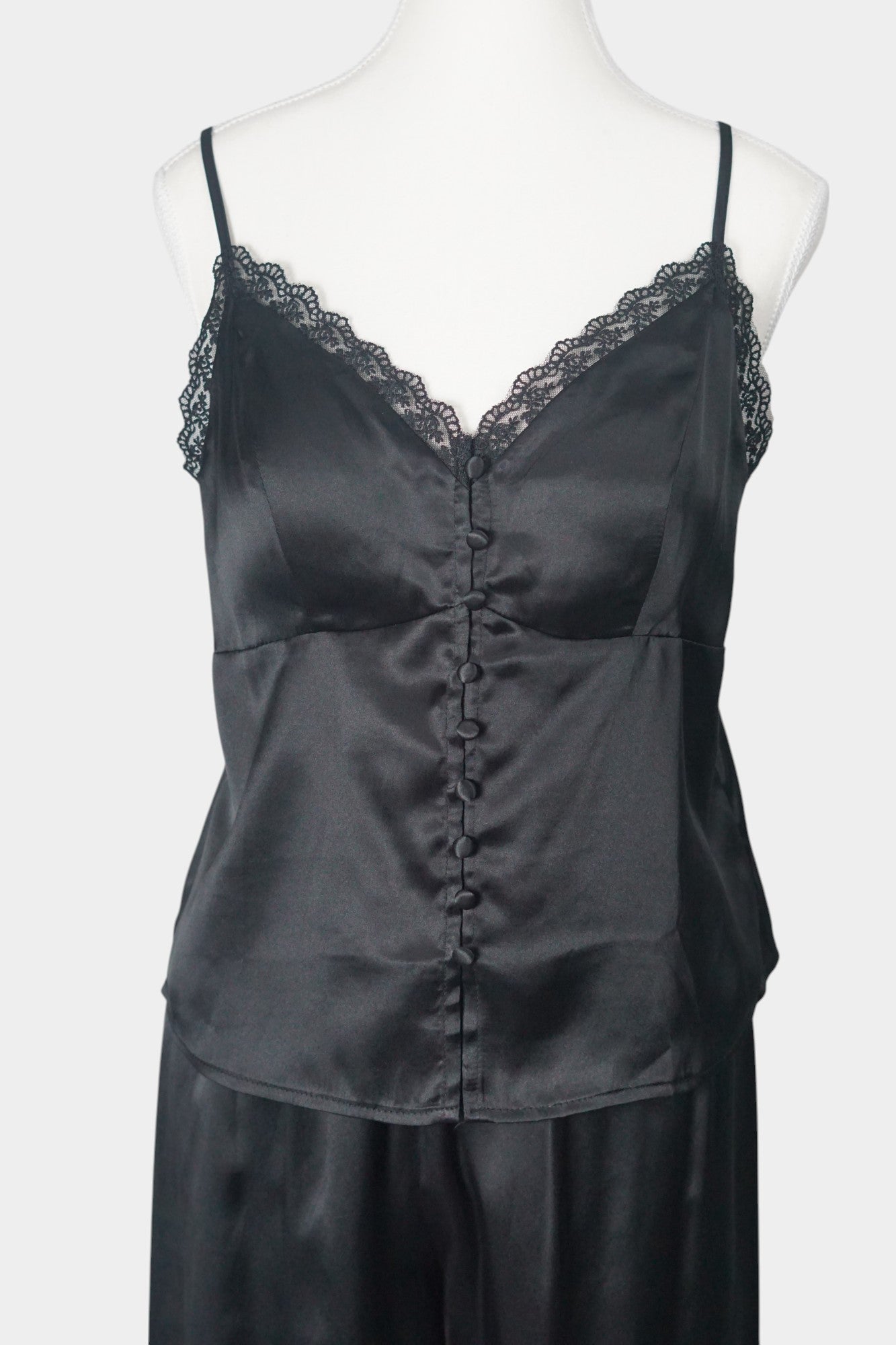 Black silk two-piece set featuring a lace-trimmed camisole top with button details and matching wide-leg trousers.