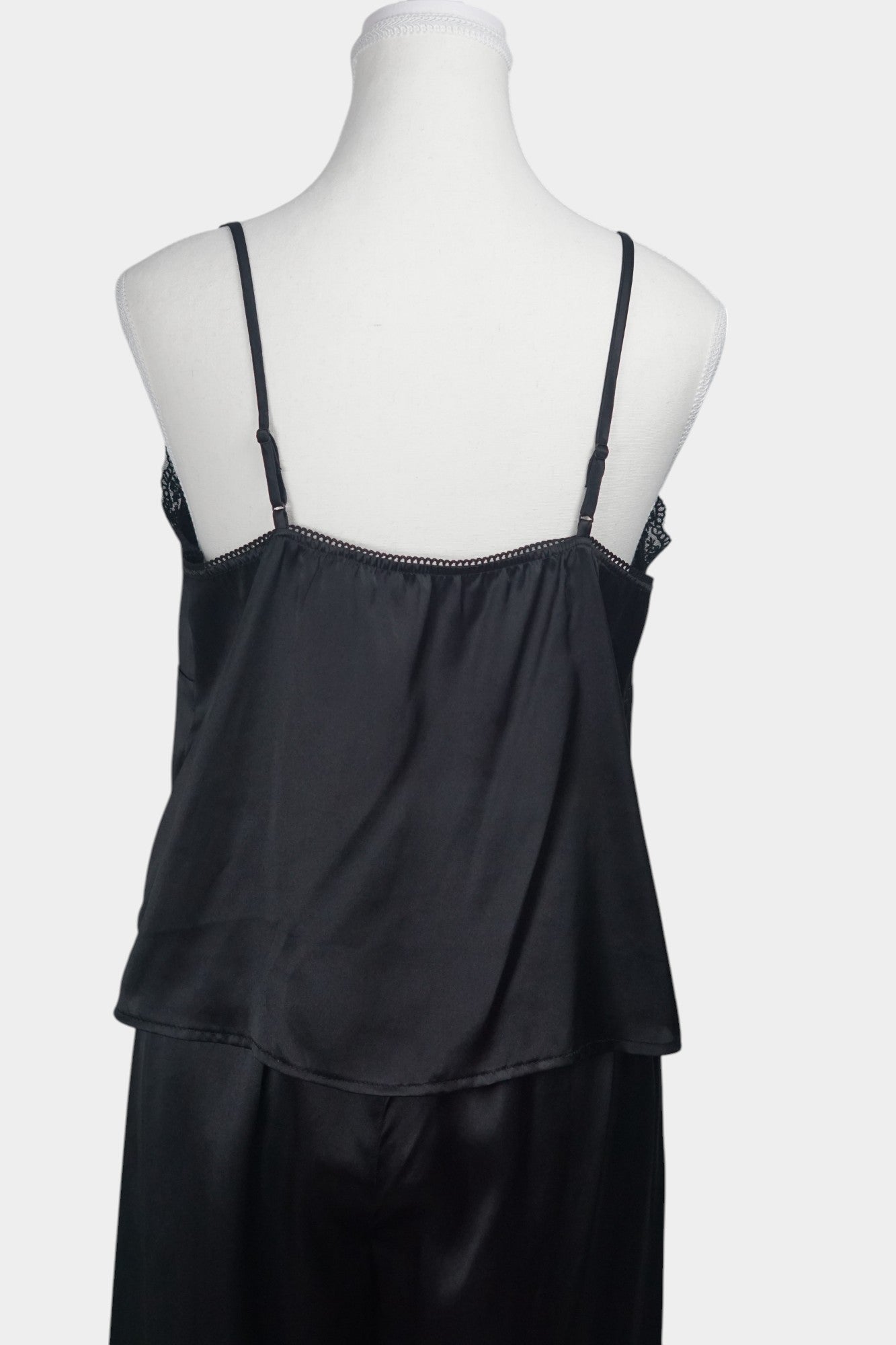 Black silk two-piece set featuring a lace-trimmed camisole top with button details and matching wide-leg trousers.