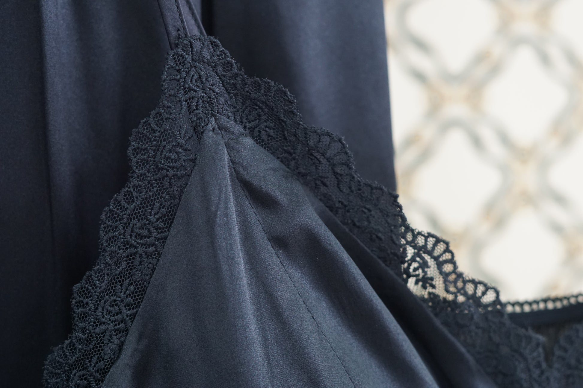 Black silk two-piece set featuring a lace-trimmed camisole top with button details and matching wide-leg trousers.