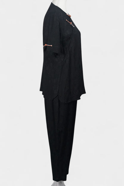 Black textured silk two-piece set featuring a short-sleeve top with contrast frog buttons and matching lantern pants