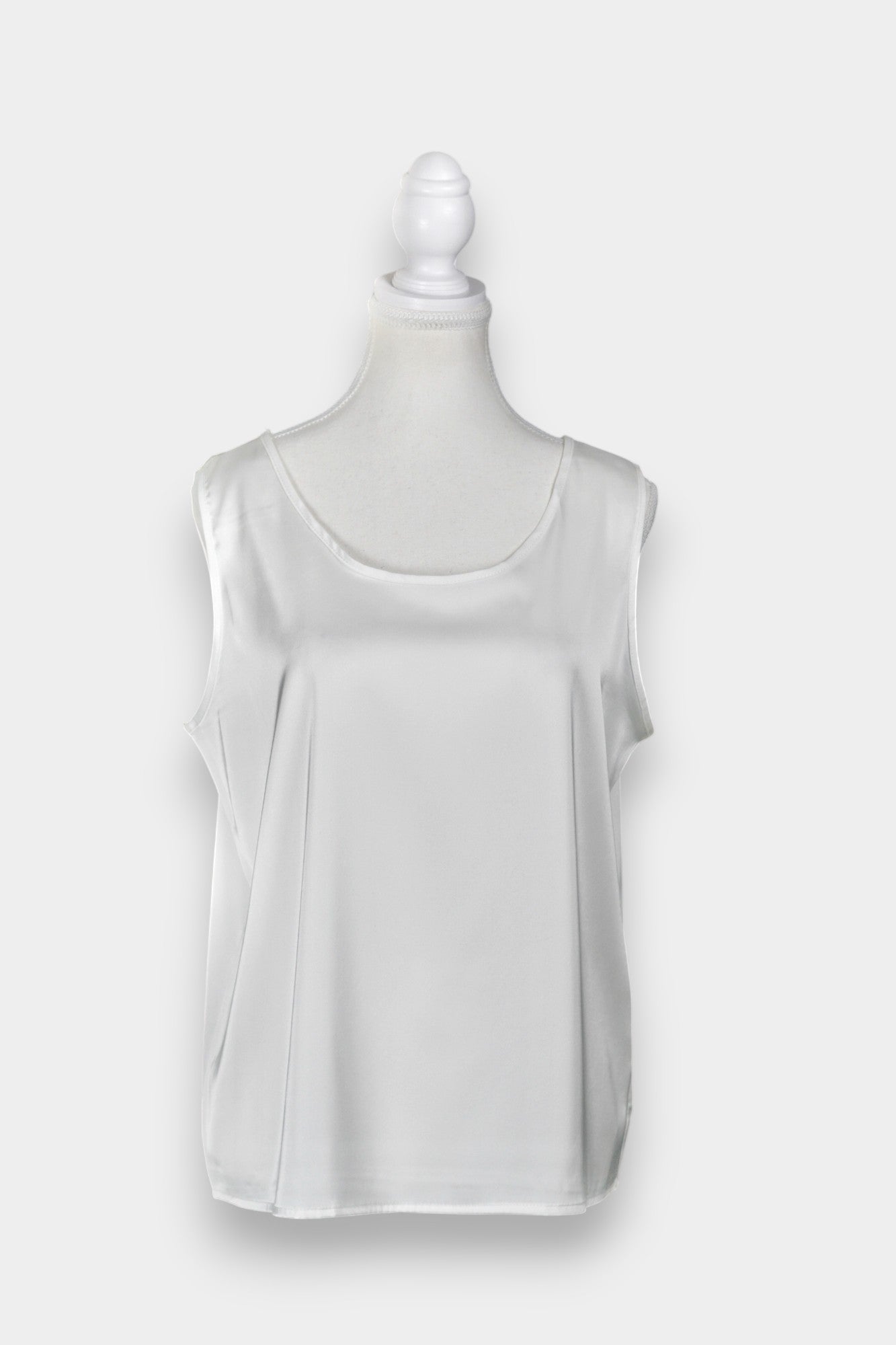 Women's white sleeveless silk top with a scoop neckline on a mannequin.
