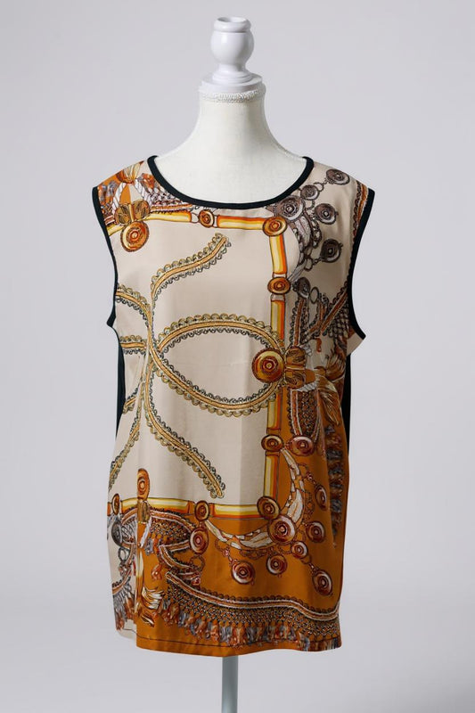 Women's sleeveless beige silk top with gold chain and tassel scarf print and black trim.