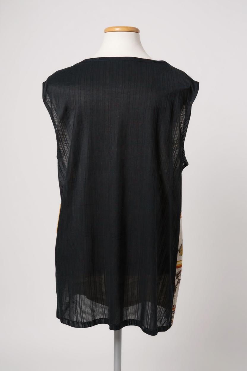 Women's sleeveless beige silk top with gold chain and tassel scarf print and black trim.