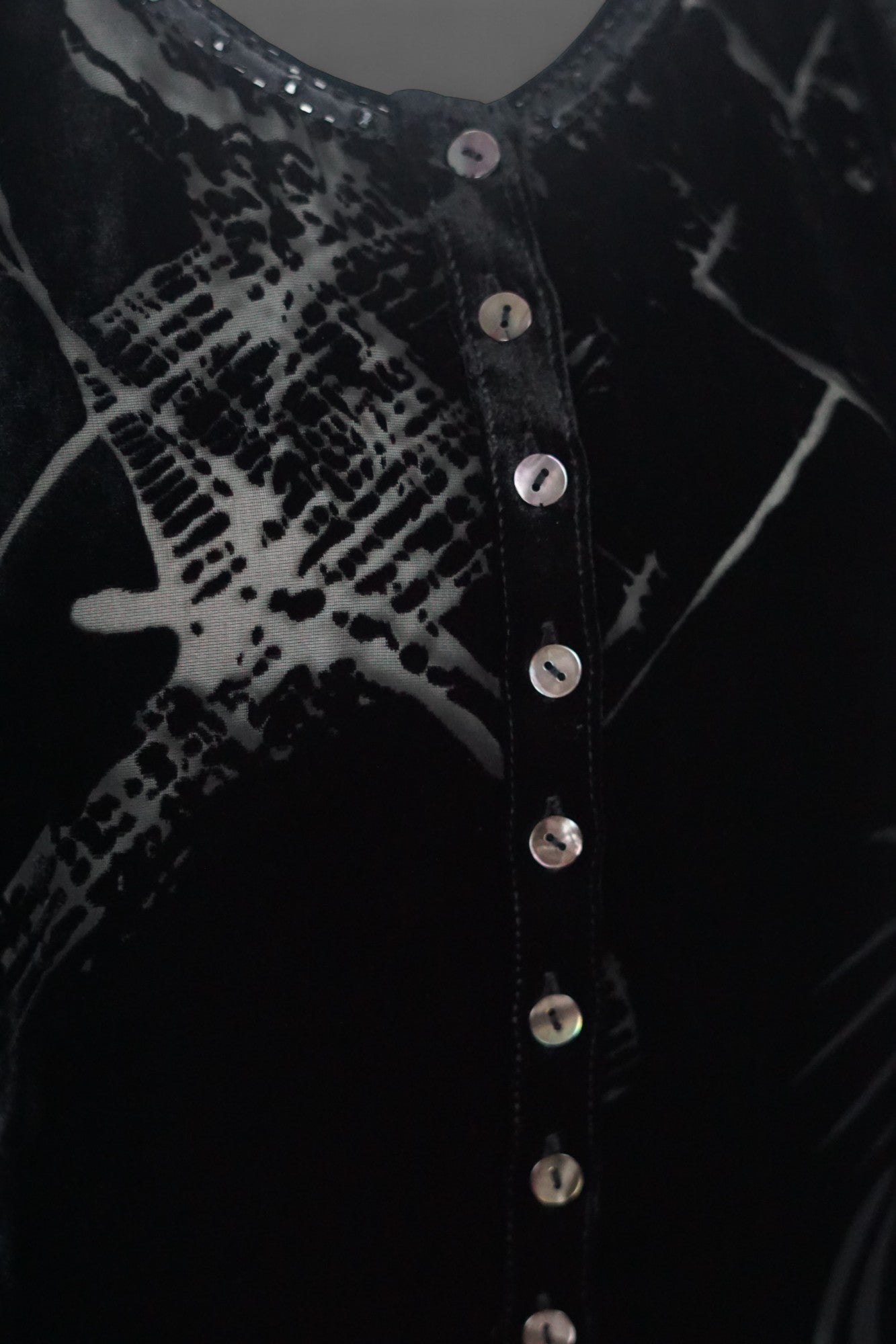 Women's black silk Henley top with grey abstract sketch patterns, buttons, and drawstring hem on a mannequin.