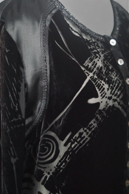 Women's black silk Henley top with grey abstract sketch patterns, buttons, and drawstring hem on a mannequin.