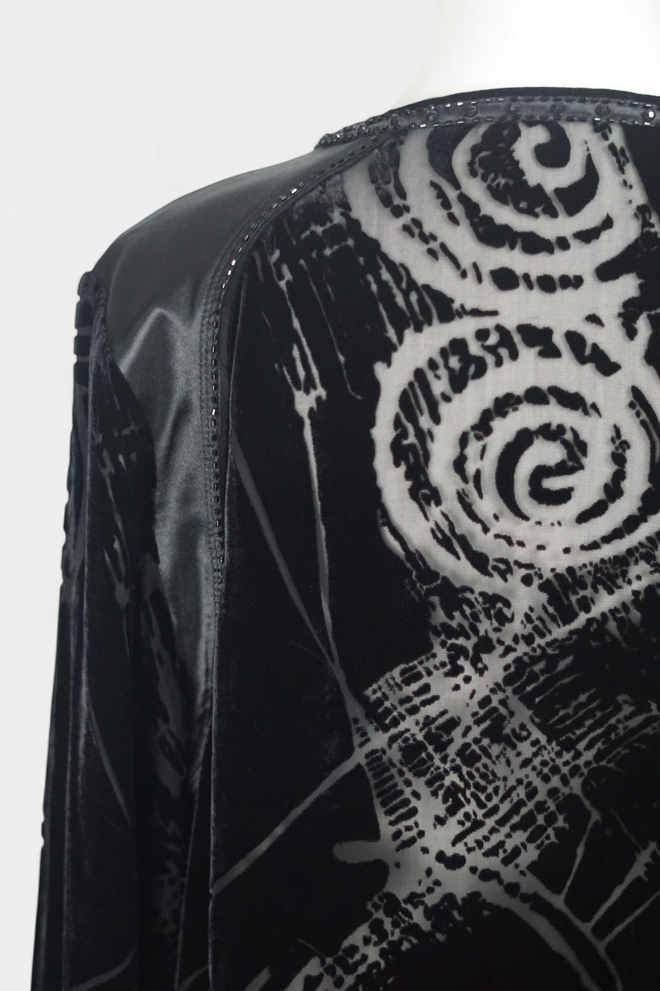 Women's black silk Henley top with grey abstract sketch patterns, buttons, and drawstring hem on a mannequin.