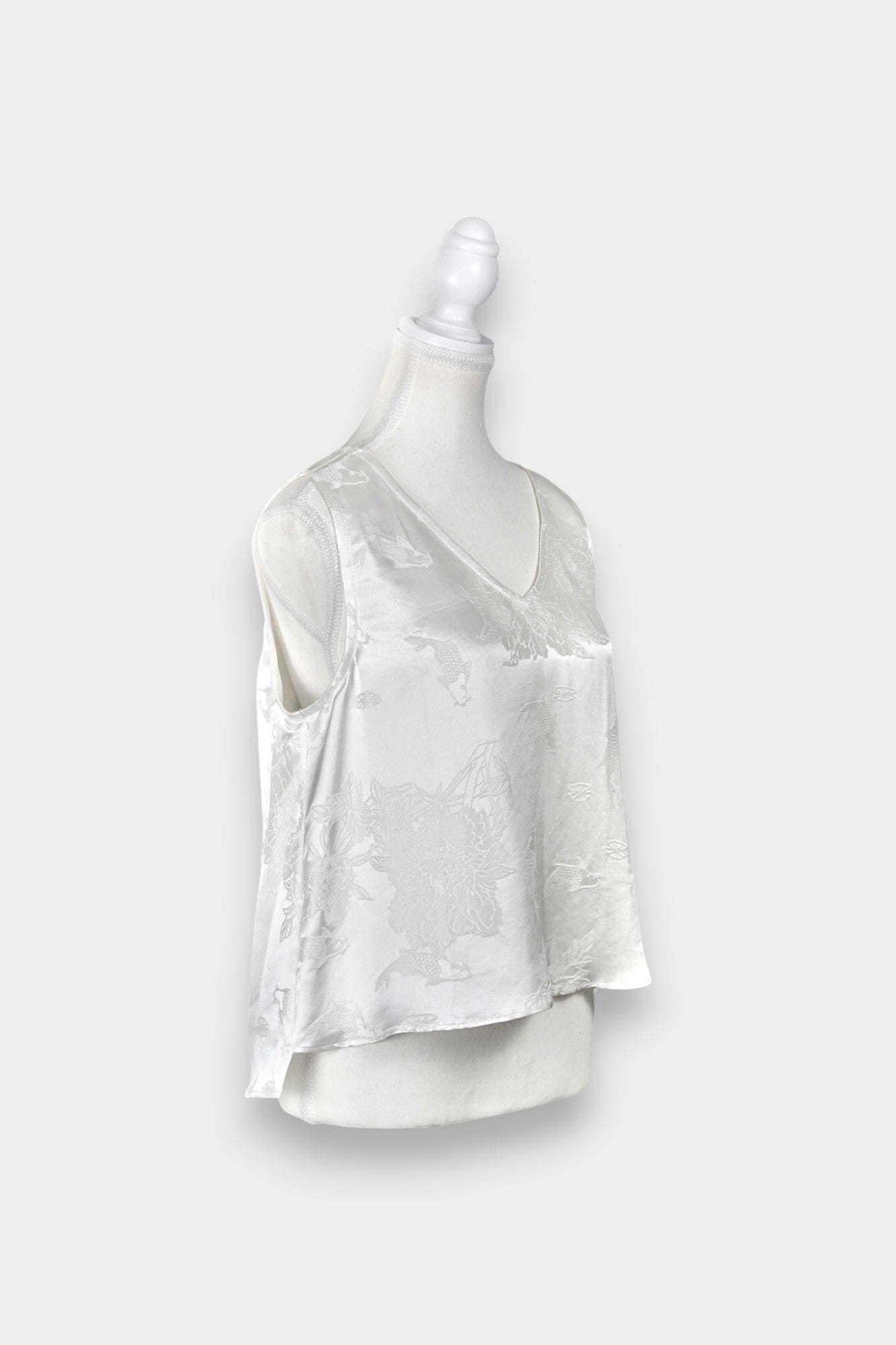 Women's white silk V-neck top with subtle woven koi fish and lotus flower jacquard patterns.