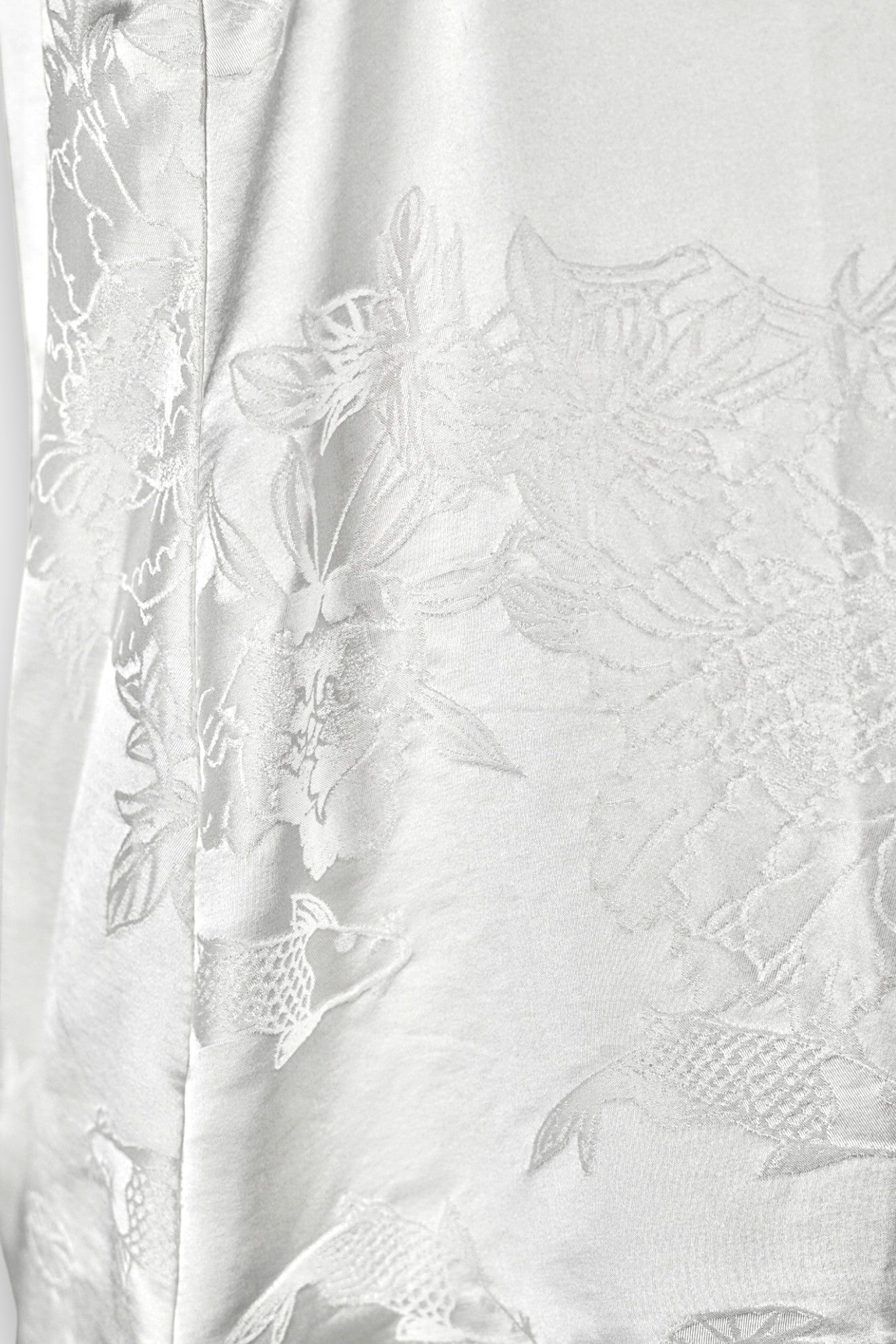 Women's white silk V-neck top with subtle woven koi fish and lotus flower jacquard patterns.