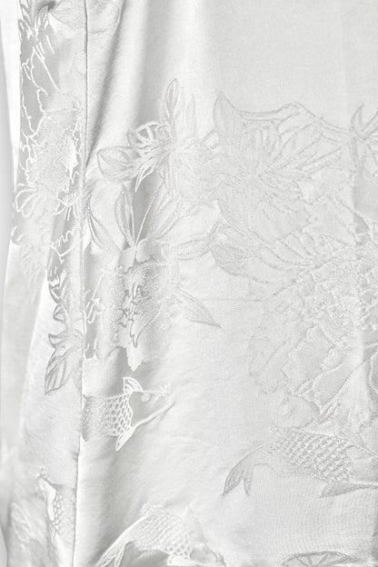 Women's white silk V-neck top with subtle woven koi fish and lotus flower jacquard patterns.