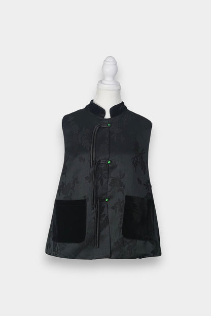 Sleeveless black vest featuring subtle floral jacquard patterns, a velvet Mandarin collar, two velvet patch pockets, and three decorative frog buttons with green beads and long tassels.