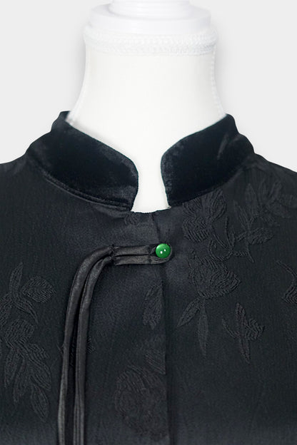 Sleeveless black vest featuring subtle floral jacquard patterns, a velvet Mandarin collar, two velvet patch pockets, and three decorative frog buttons with green beads and long tassels.