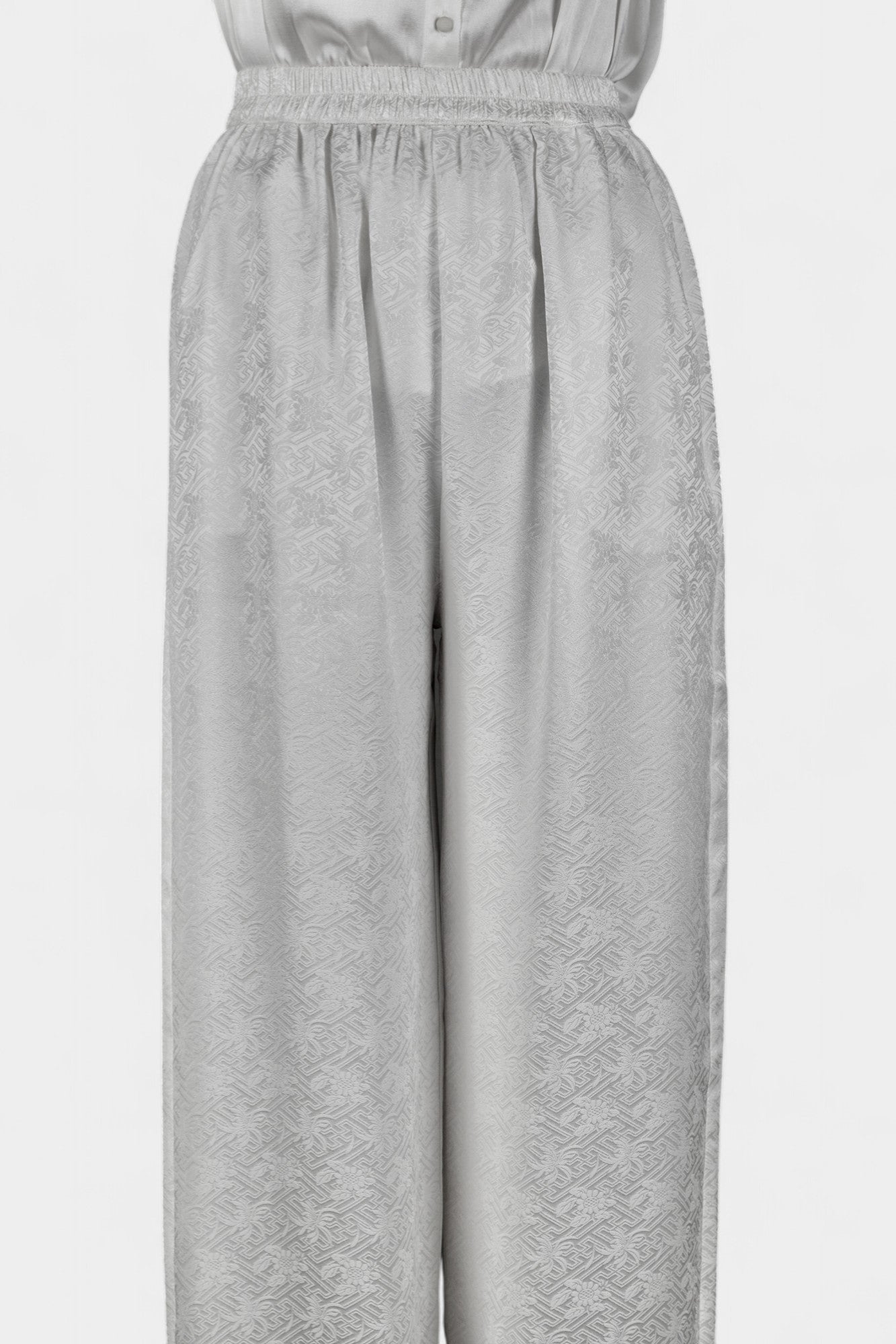 Pearl white wide-leg silk trousers featuring a subtle geometric jacquard pattern and elastic waistband