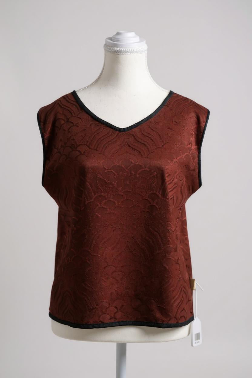 Rust red side of a reversible Gambiered Guangdong Gauze silk vest with black piping trim and traditional cloud pattern