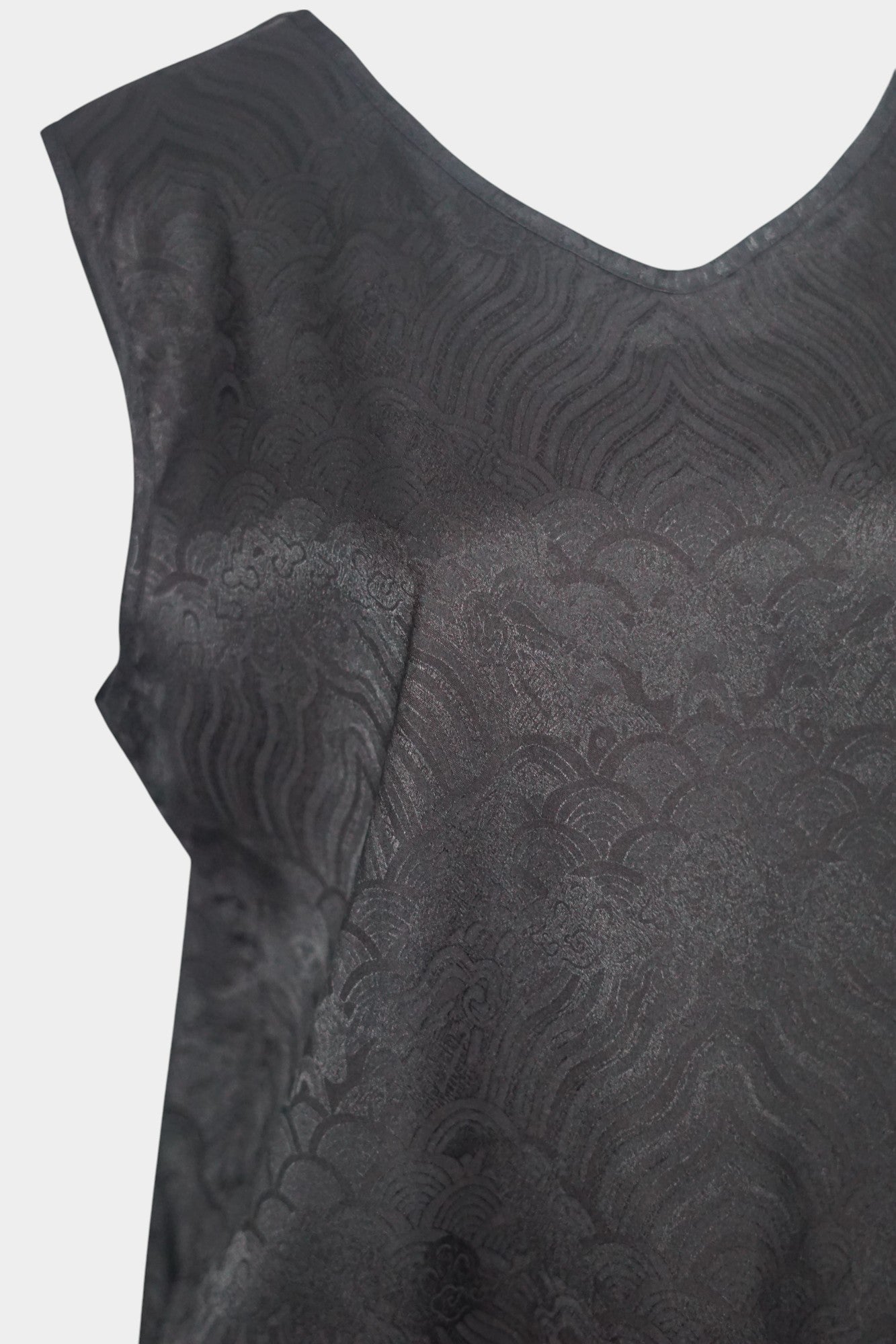 Black side of a reversible women's silk vest featuring a textured wave jacquard pattern and V-neckline.