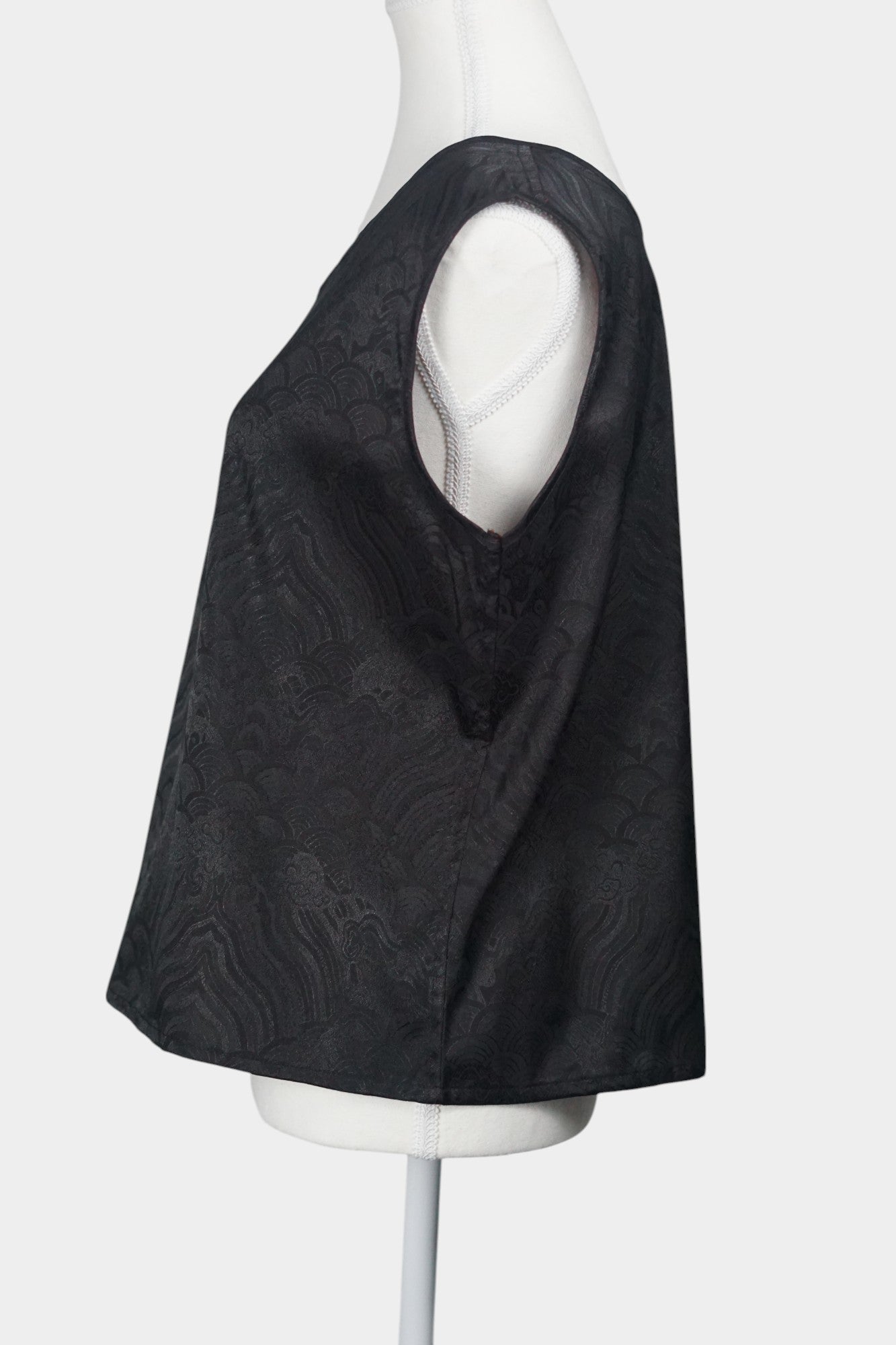 Black side of a reversible women's silk vest featuring a textured wave jacquard pattern and V-neckline.