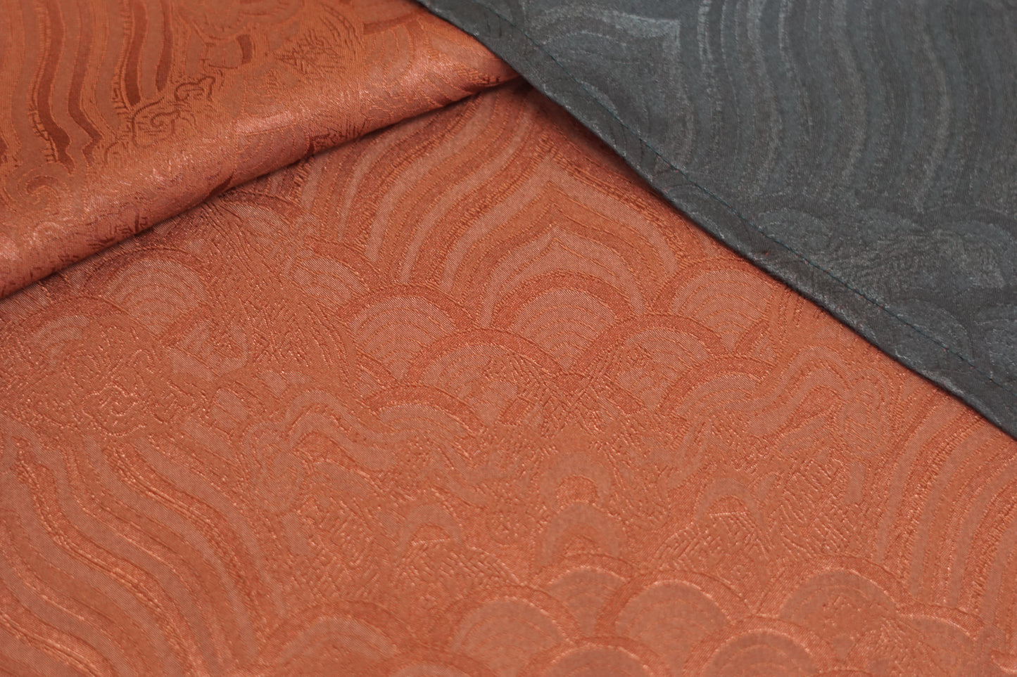 Rust red side of a reversible Gambiered Guangdong Gauze silk vest with black piping trim and traditional cloud pattern.