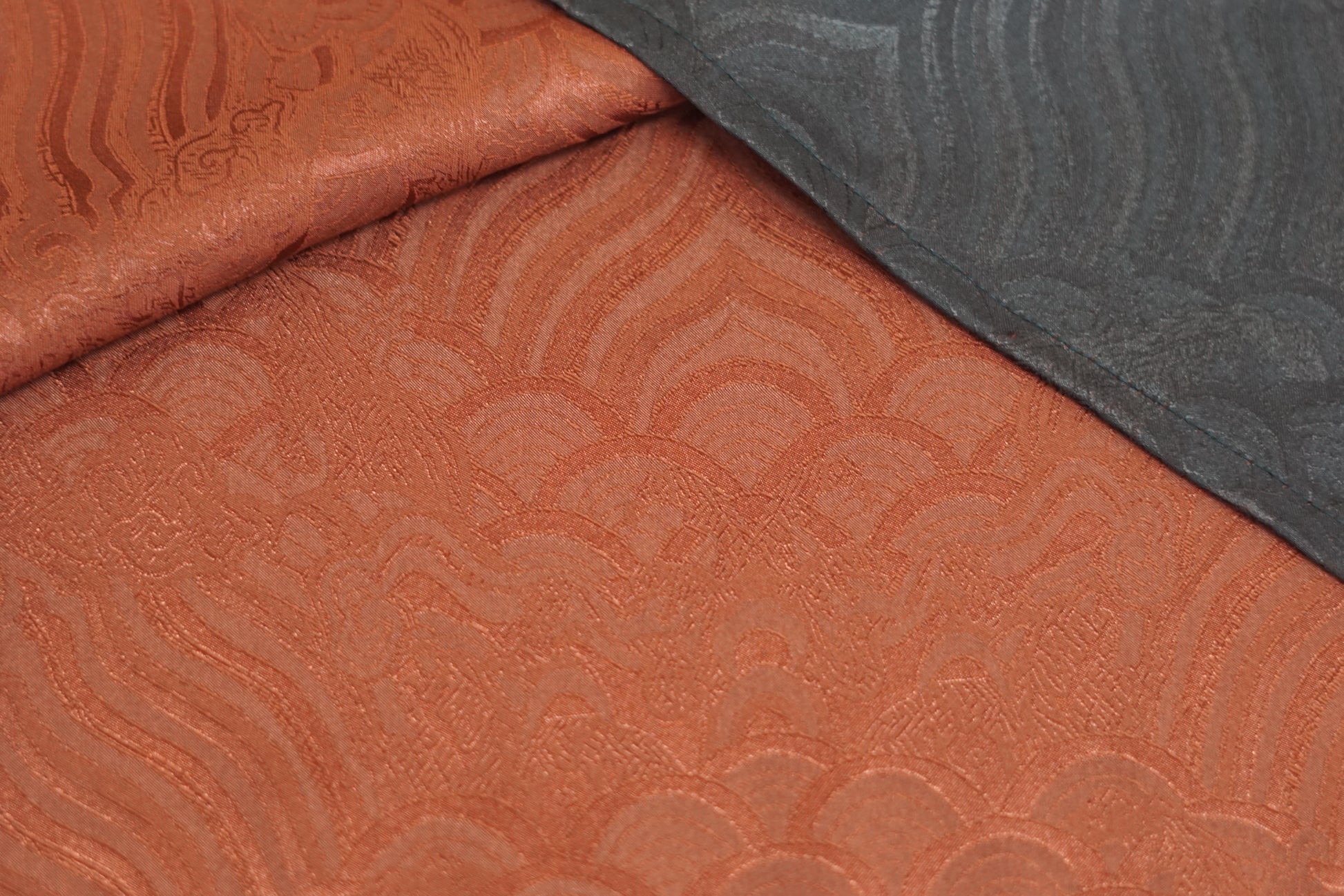 Rust red side of a reversible Gambiered Guangdong Gauze silk vest with black piping trim and traditional cloud pattern.