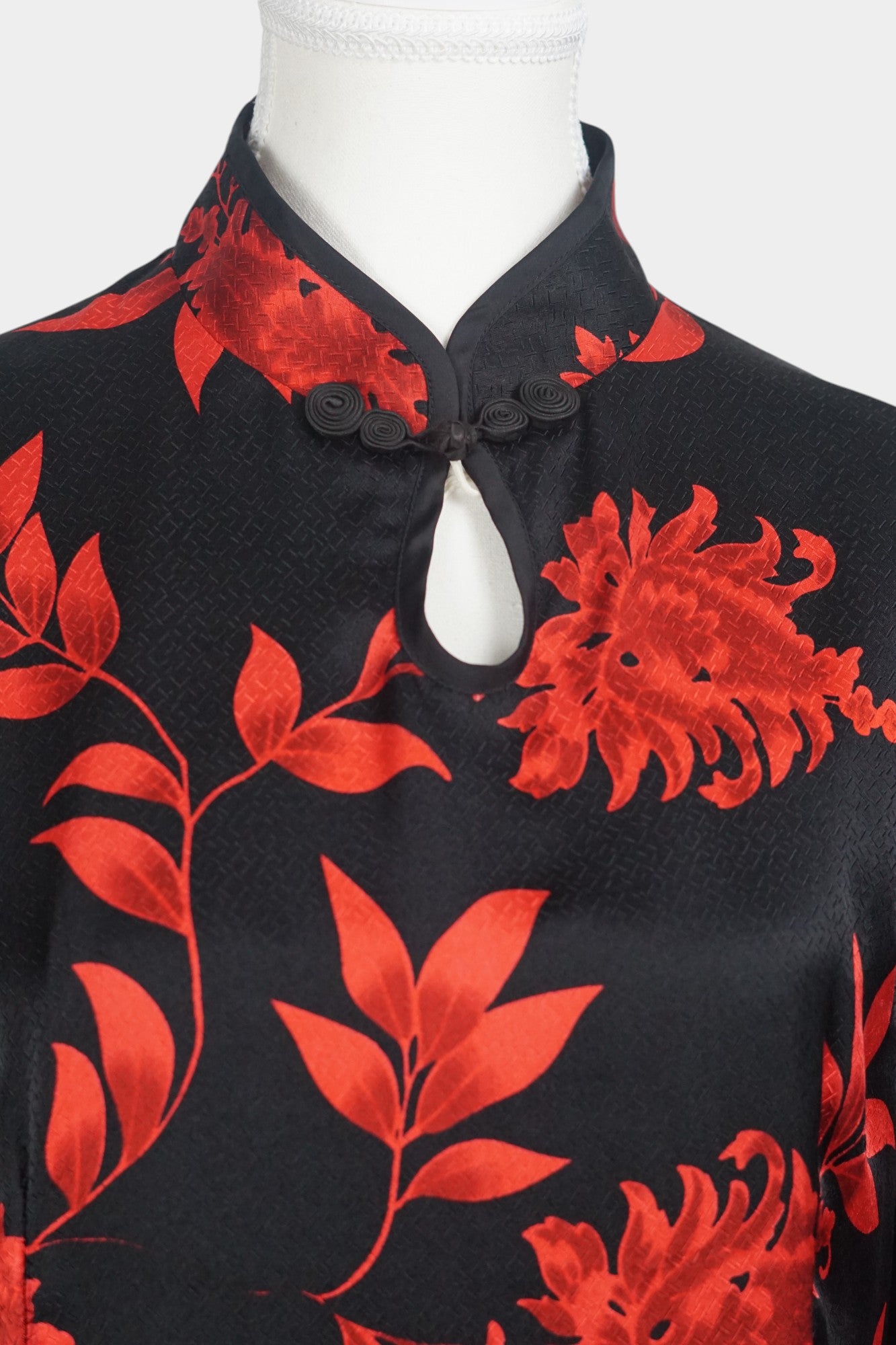 Traditional Chinese style midi dress in lustrous black fabric, adorned with vibrant red floral motifs and a teardrop cutout at the neck