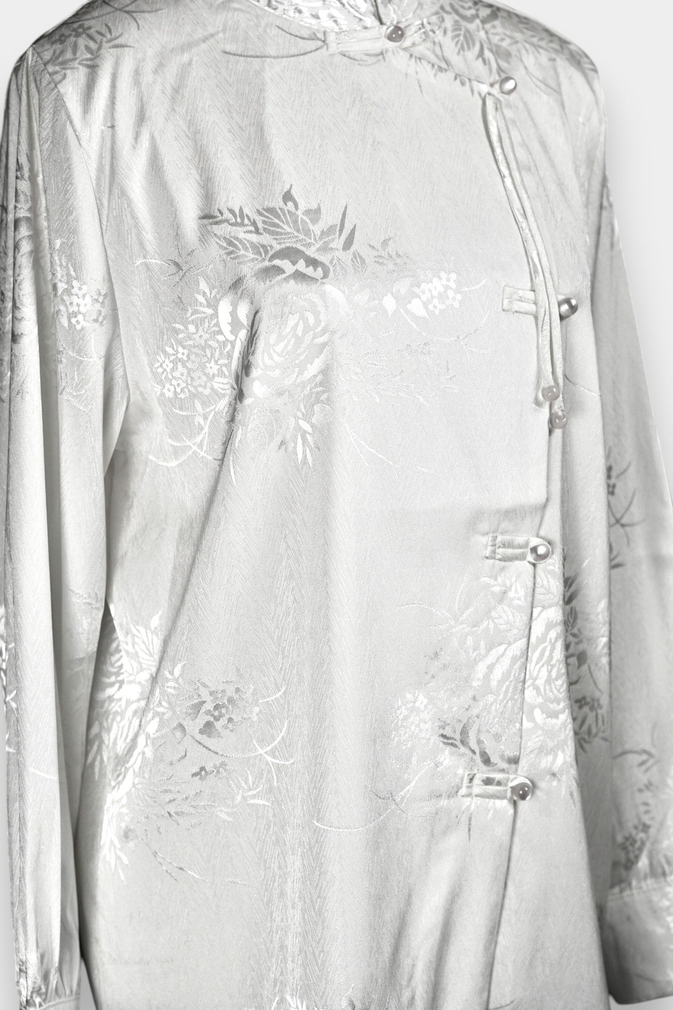 Lustrous ivory Song Jin top adorned with subtle floral patterns and a side-fastening front