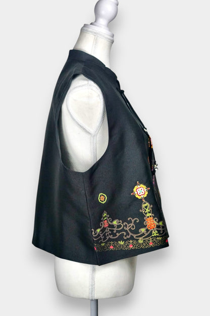 Women's black Song Brocade vest with a mandarin collar, frog buttons, and colorful woven traditional patterns on the hem.