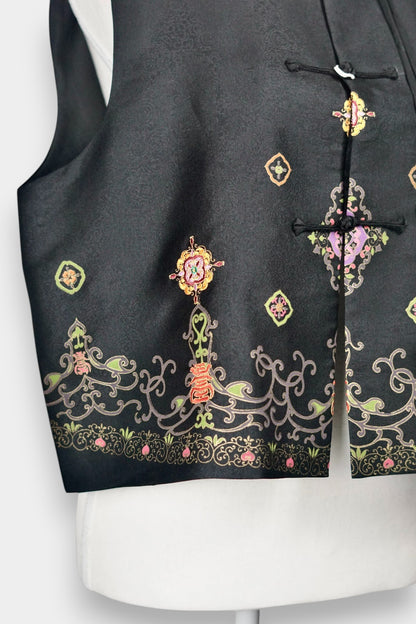 Women's black Song Brocade vest with a mandarin collar, frog buttons, and colorful woven traditional patterns on the hem.